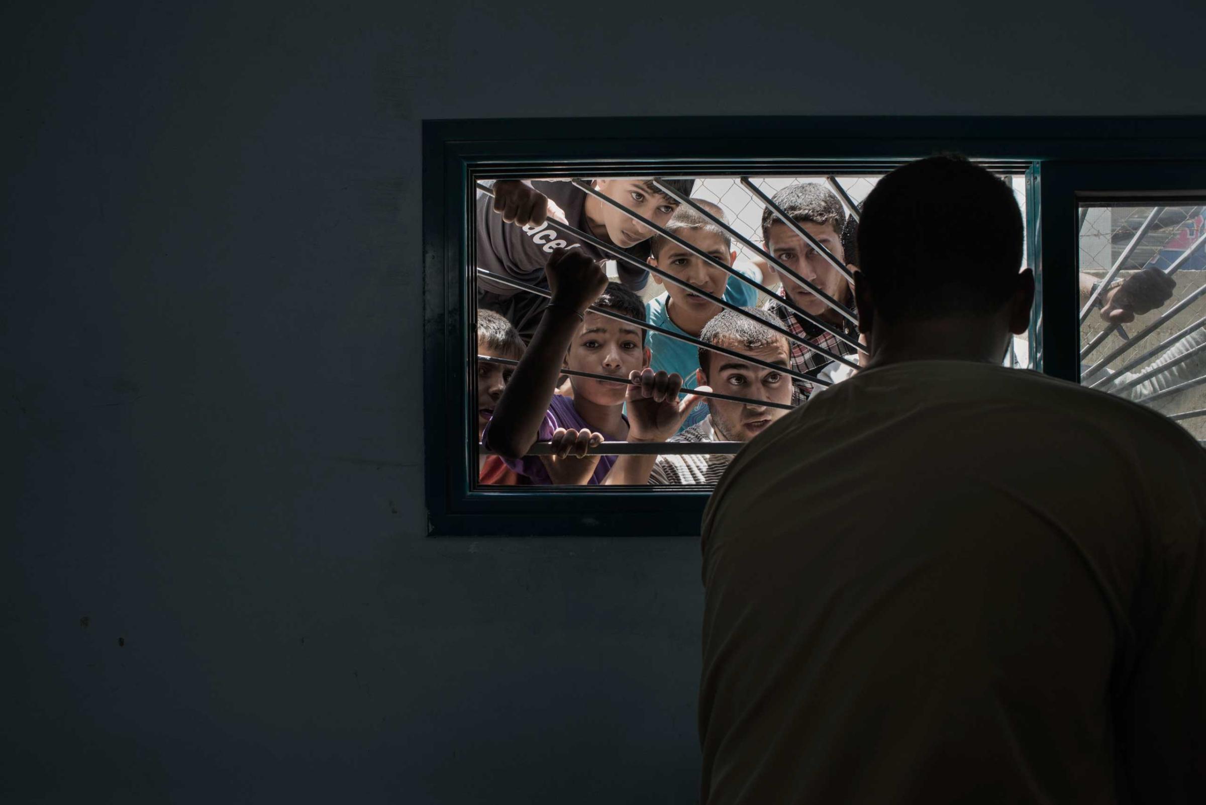 People looking through the window of the Beit Hanoun morgue, in the Gaza Strip, July 9, 2014.