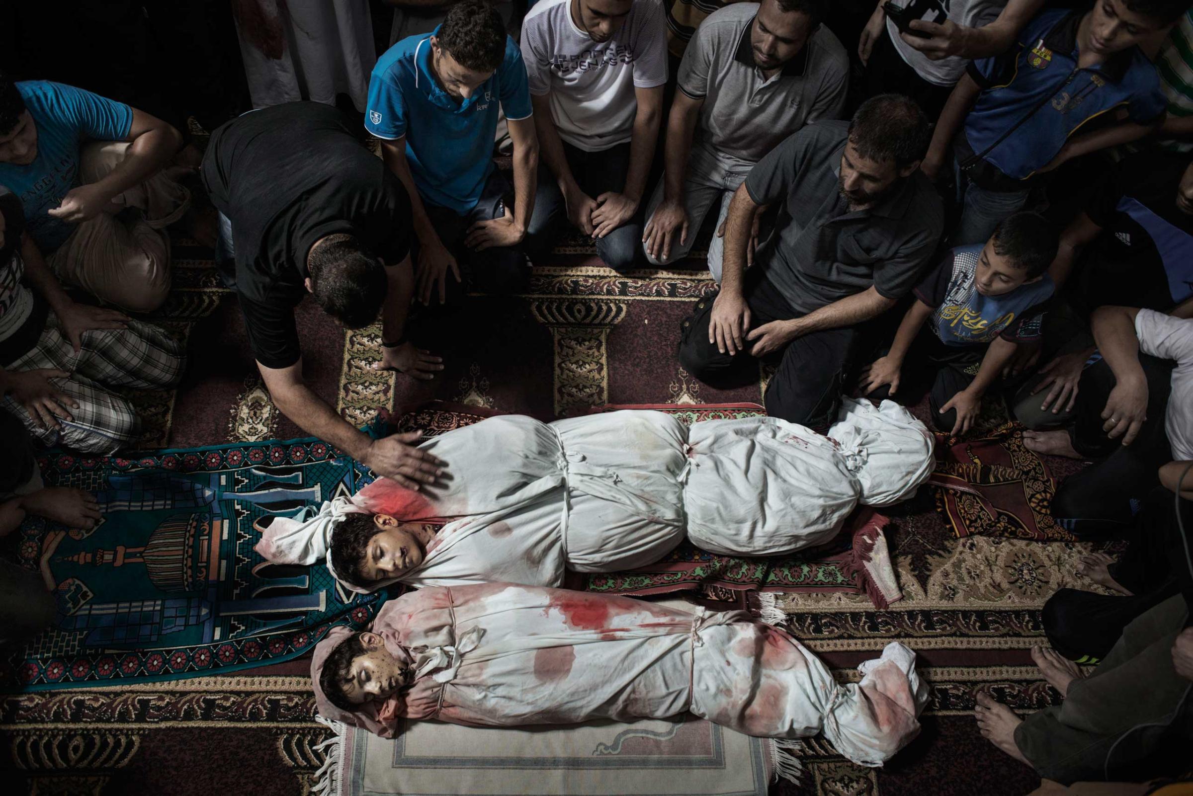 Relatives pray over the bodies of two brothers, named Amir and Mohammed, in a mosque in Gaza City, July 9, 2014.