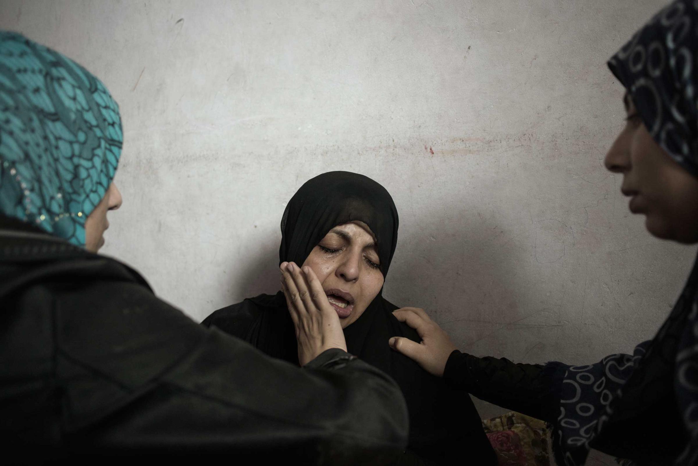 Relatives comfort Suhar Elasem as she awaits the funeral of her two sons, seven and four years old, killed by Israeli tank shells that hit their home in the northern part of Gaza City, July 19, 2014.