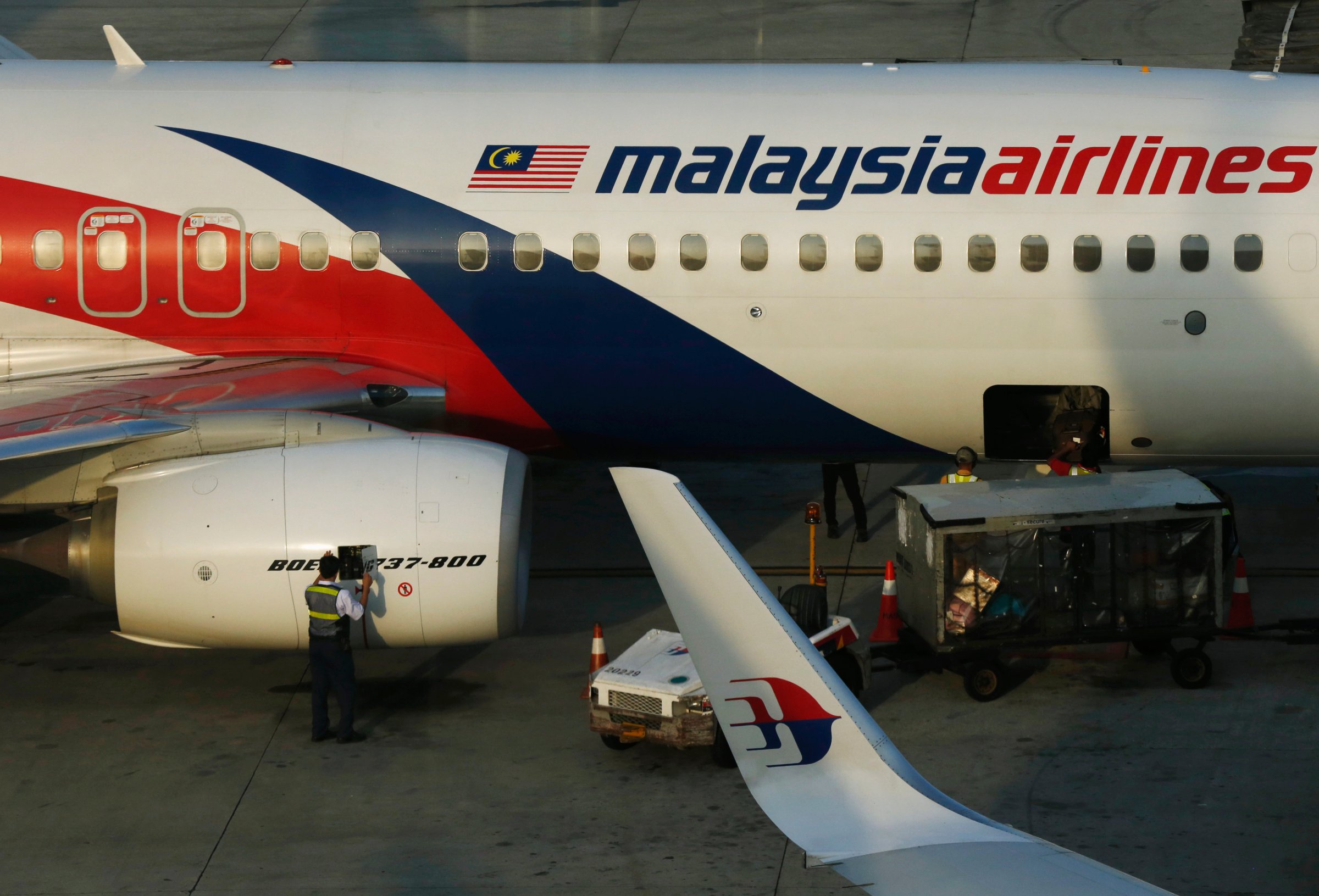A member of ground crew works on a Malaysia Airlines Boeing 737-800 airplane on the runway at Kuala Lumpur International Airport in Sepang