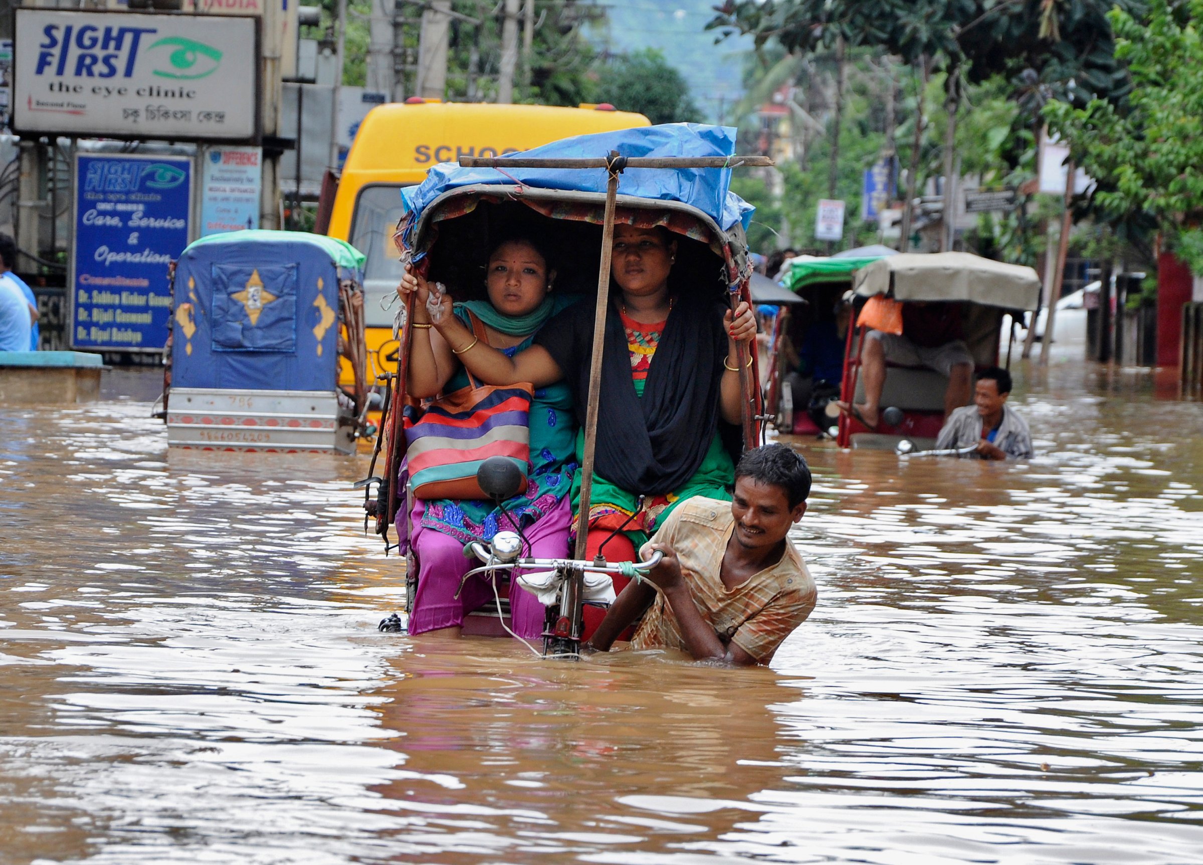 People use cycle rickshaws to commute through a flooded road after heavy rains in Guwahati