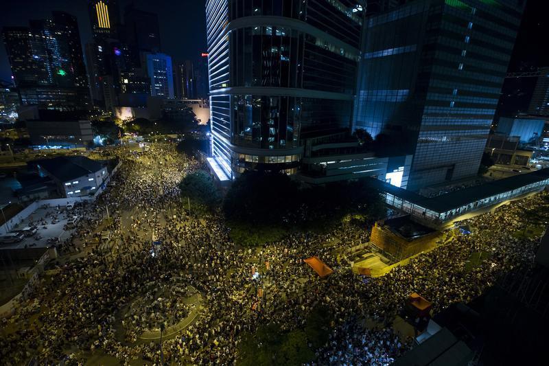 Thousands of protesters attend a rally outside the government headquarters in Hong Kong as riot police stand guard on Sept. 27, 2014 (Tyrone Siu— Reuters)