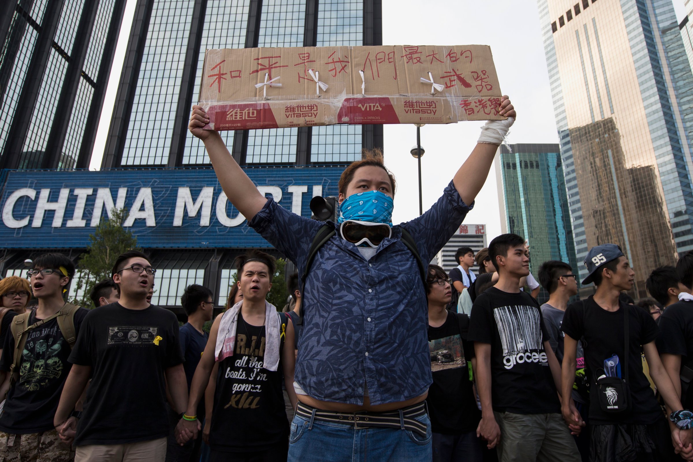 A protester holds up a placard which reads "Peace is our greatest weapon", outside the venue of the official flag-raising ceremony for celebrations of China's National Day, in Hong Kong