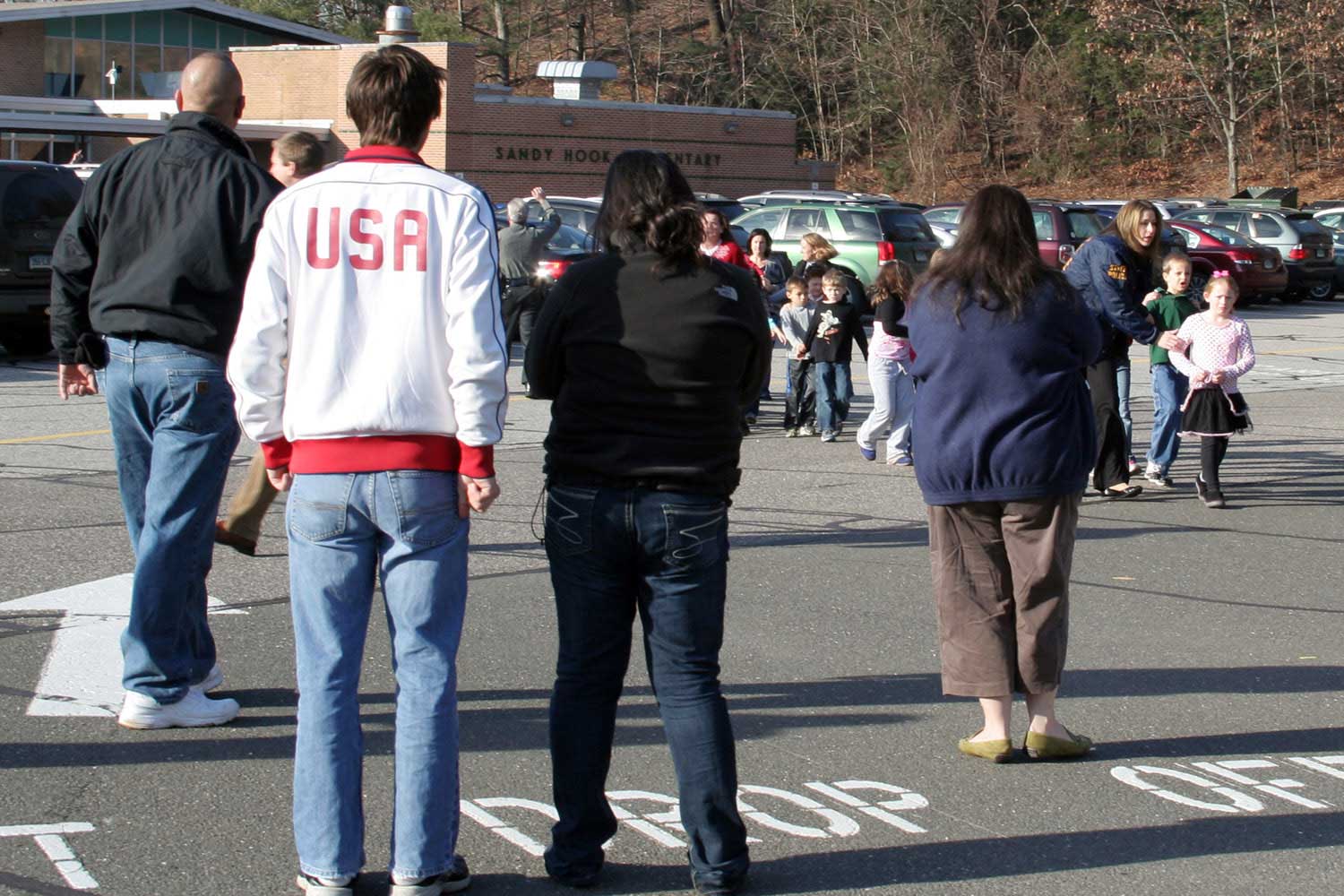 People look on as students are led out of Sandy Hook Elementary School in Newtown, Conn.