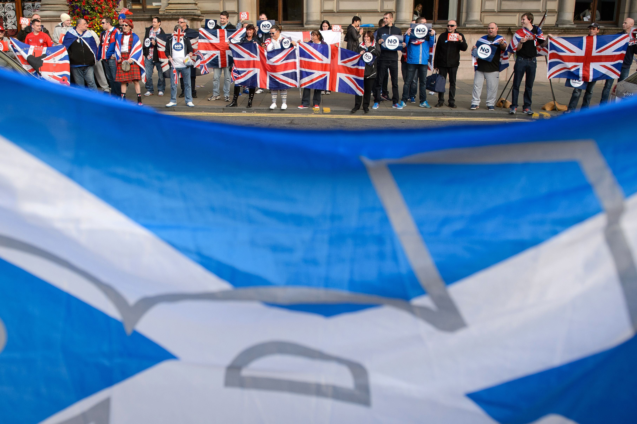 Pro-independence supporters' Scottish flag seen in front pro-union activists in Glasgow's George Square, in Scotland, on Sept. 17, 2014, on the eve of Scotland's independence referendum.