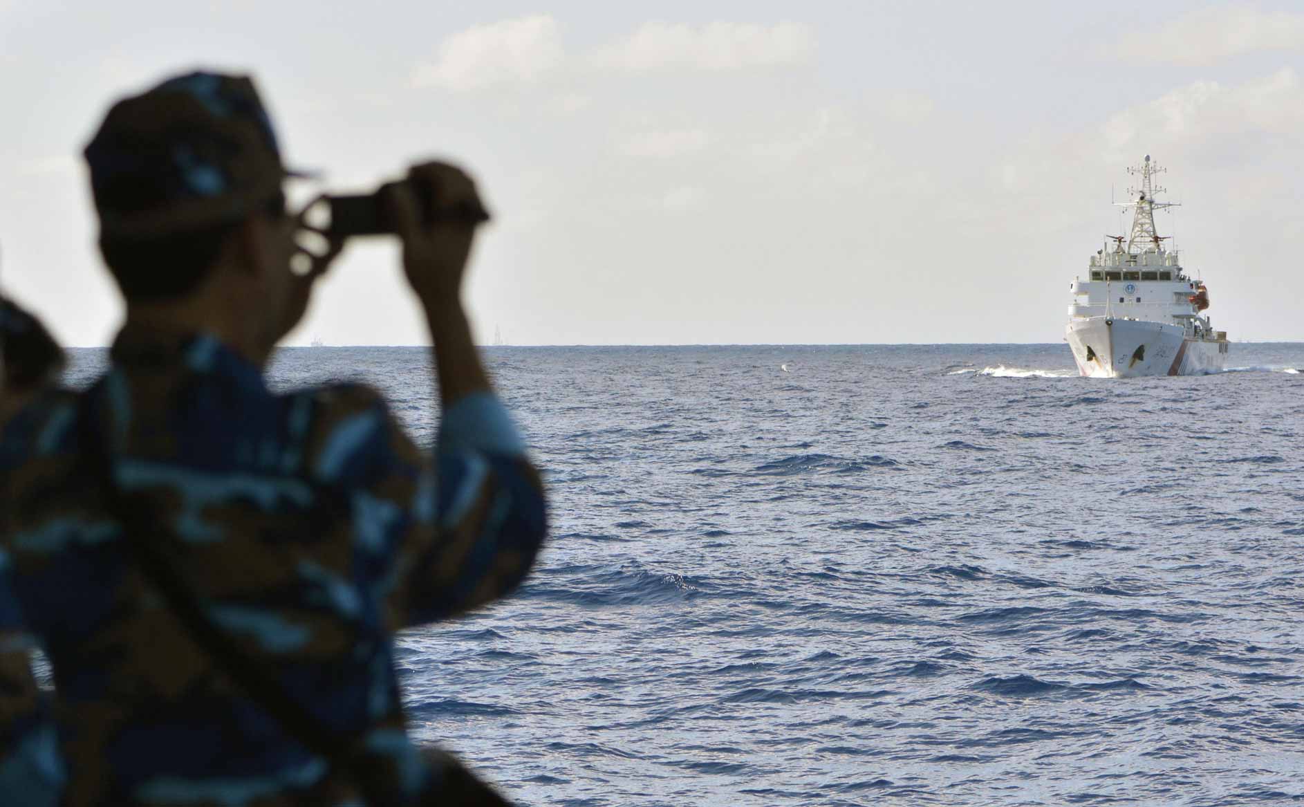 South China Sea, a crew member of a Vietnamese coast-guard vessel monitors the movements of a Chinese patrol ship