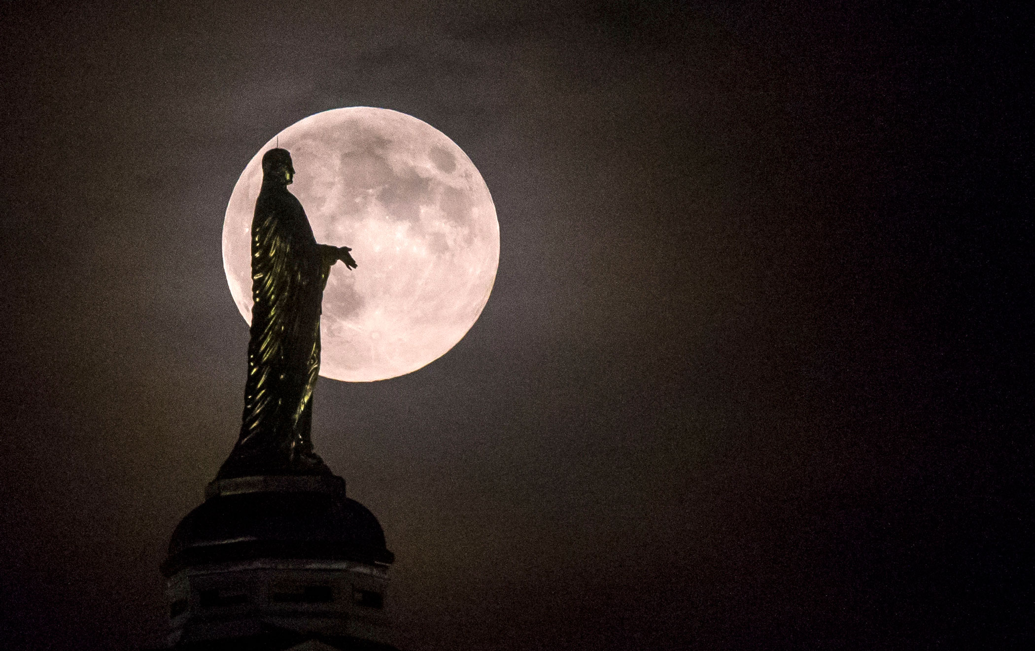 The harvest supermoon silhouettes the statue of the Virgin Mary on top the University of Notre Dame's golden dome in South Bend, Ind., on Sept. 8, 2014.