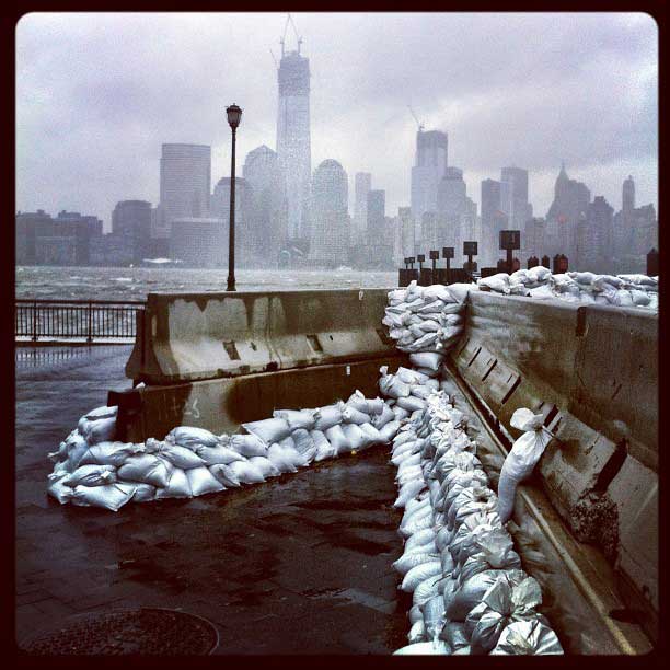 Sandbags line the waterfront of downtown Jersey City, N.J., with the unfinished World Trade Center towering over lower Manhattan across the roiling Hudson River
