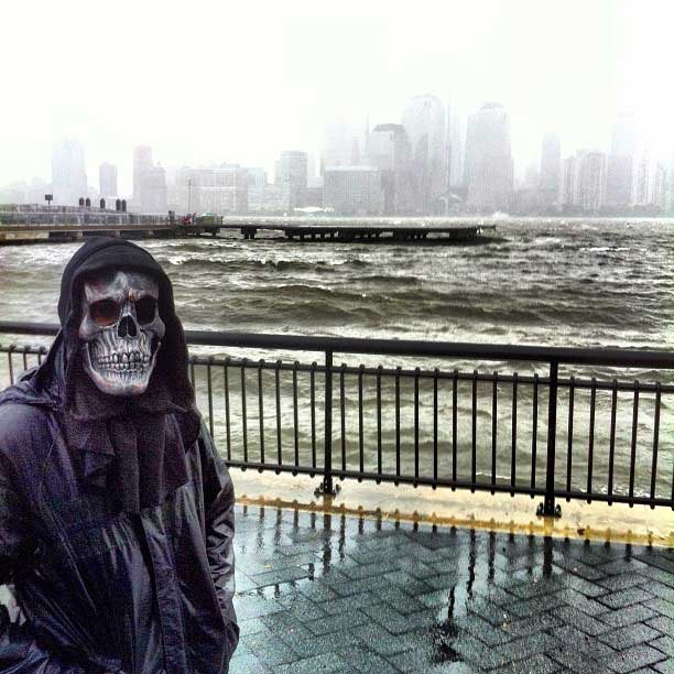 An early Halloween reveler walks along the Jersey City harbor, in New Jersey, as the Hudson River churns