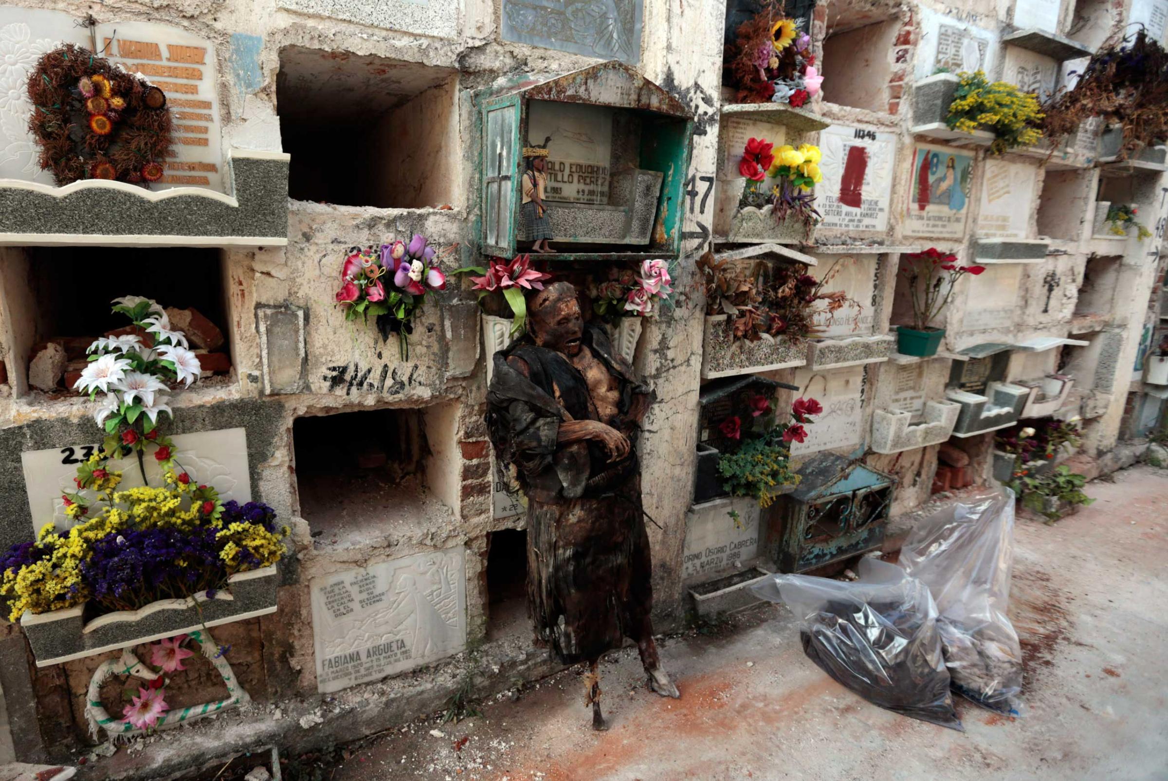 A mummified body is seen leaning on niches after it was exhumed at the municipal cemetery in Guatemala City