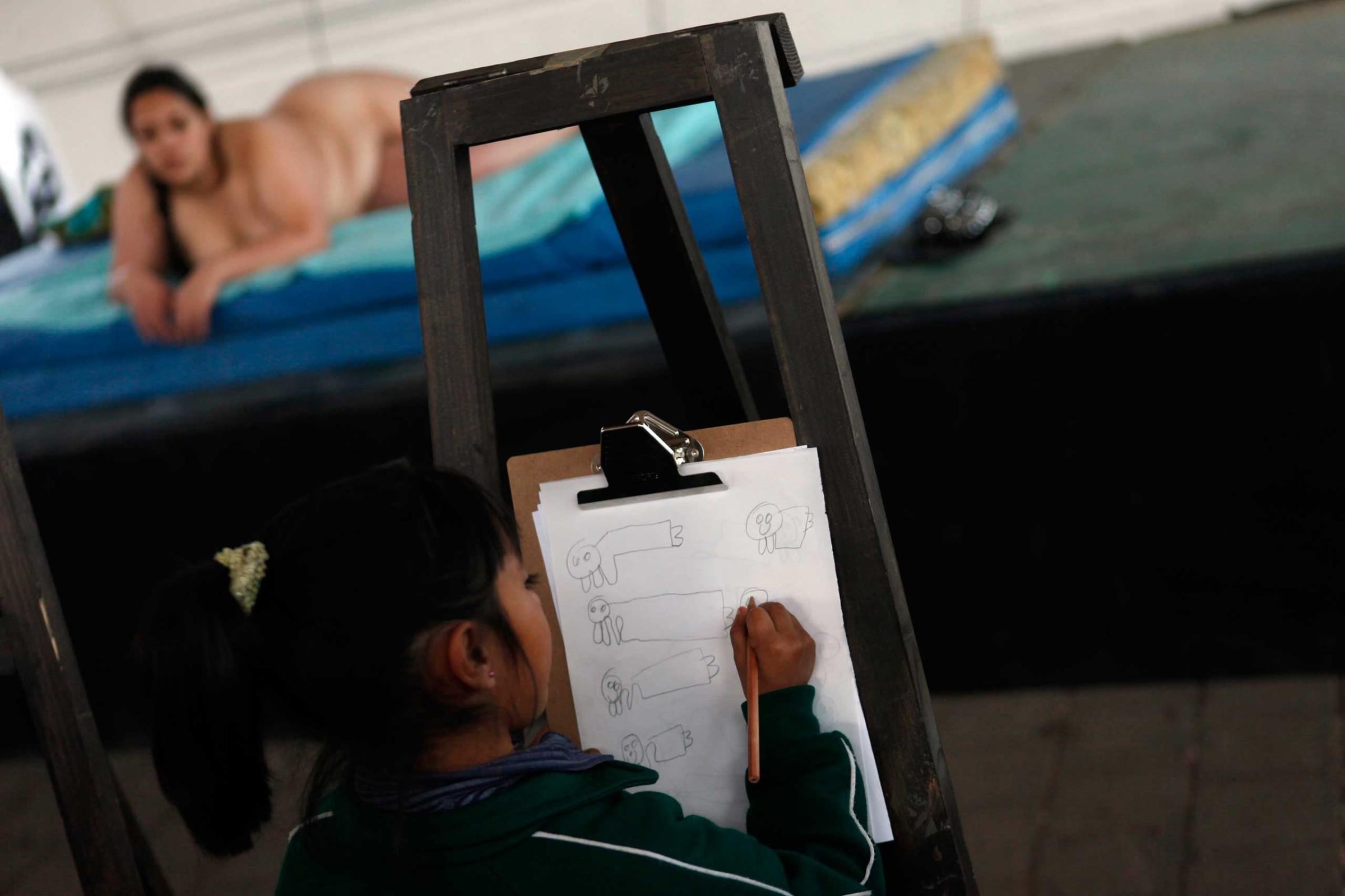 A model poses nude while a girl draws her during drawing workshop on Valentine's Day in Mexico City