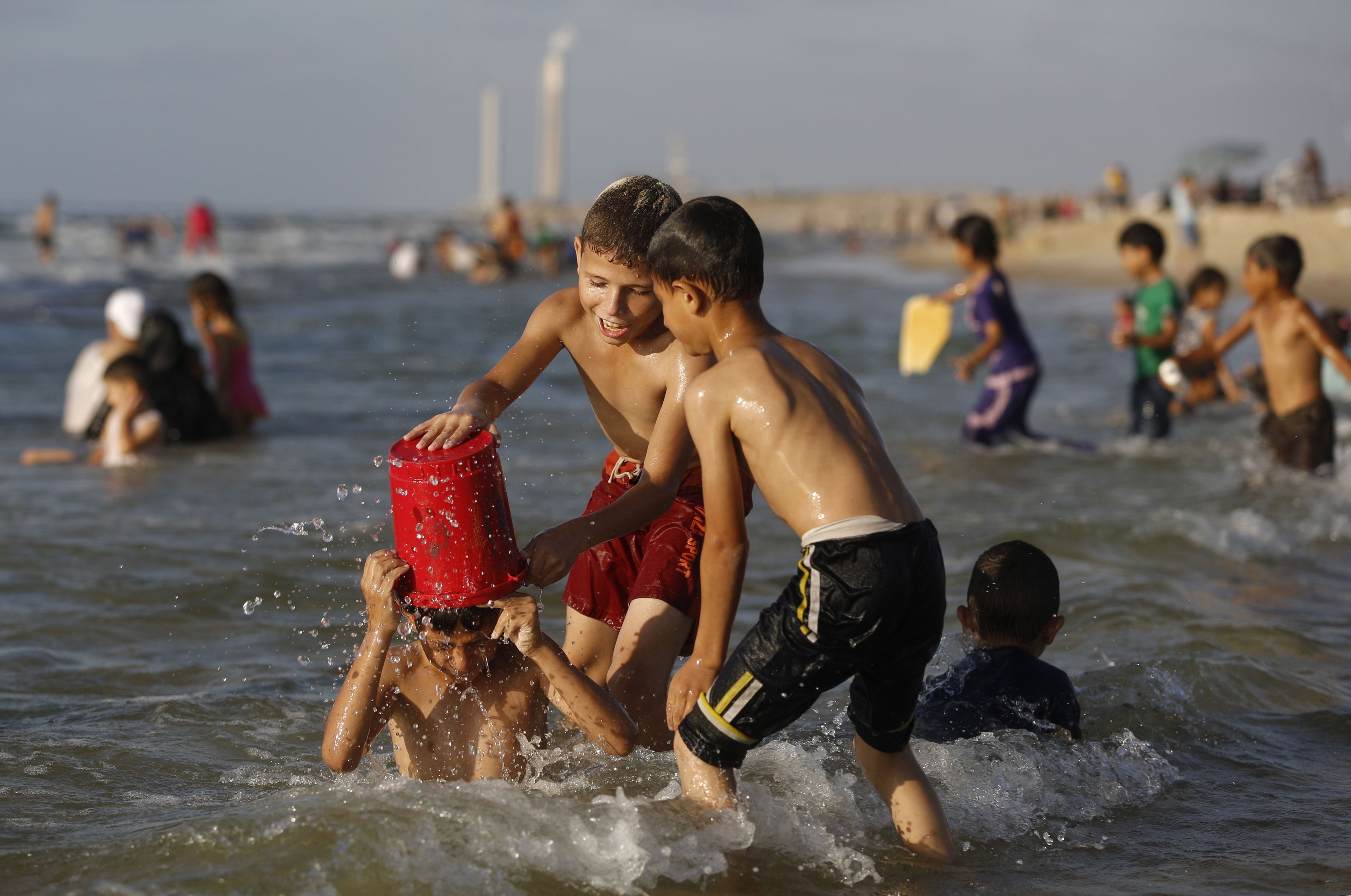 Palestinian children dump water on a boy as they swim on a beach, close to the divide with Israel, near Gaza City on Sept. 12, 2014. (Mohammed Abed—AFP/Getty Images)