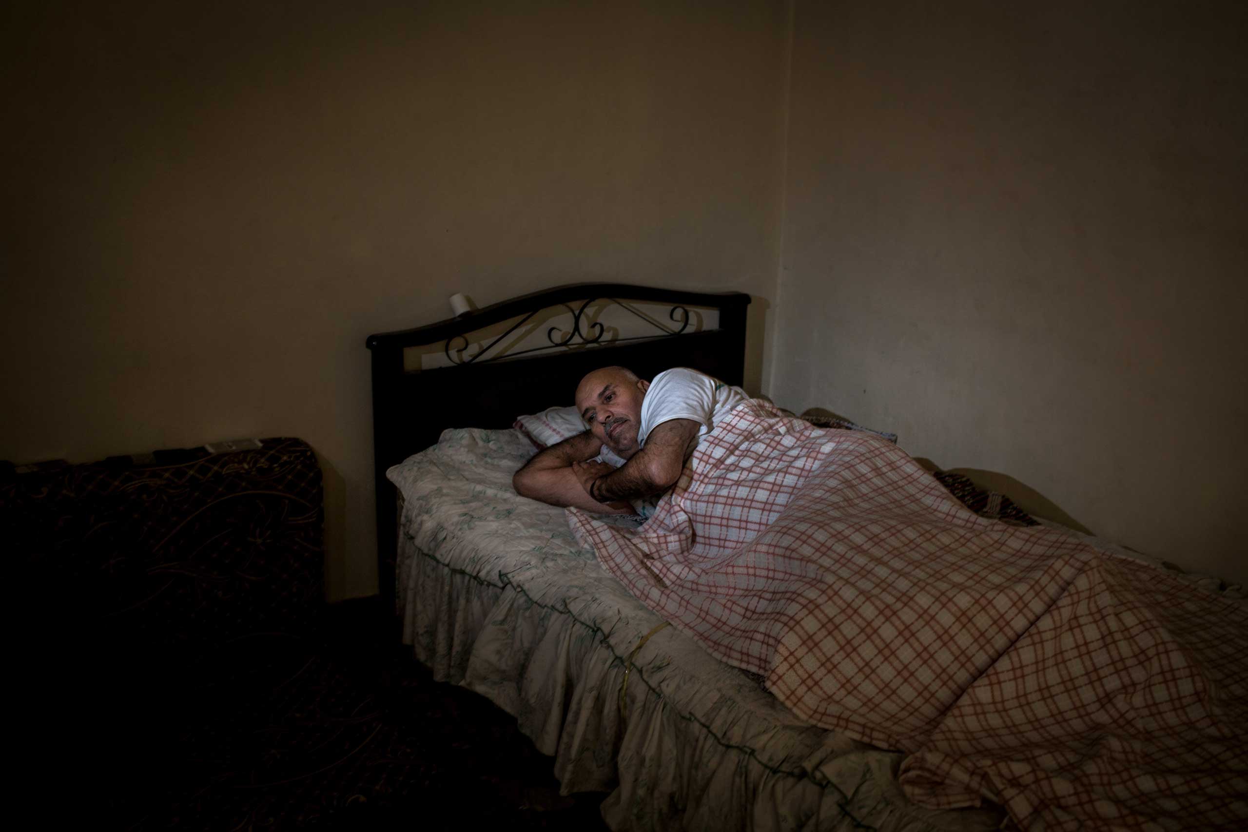 Ali, 54, lies in a bed in Zahle, Lebanon, June 26, 2014. Shelling and shooting in Awar, Syria, in April 2013 left him paralyzed from the waist down. His lack of movement has resulted in bedsores and he needs additional care.