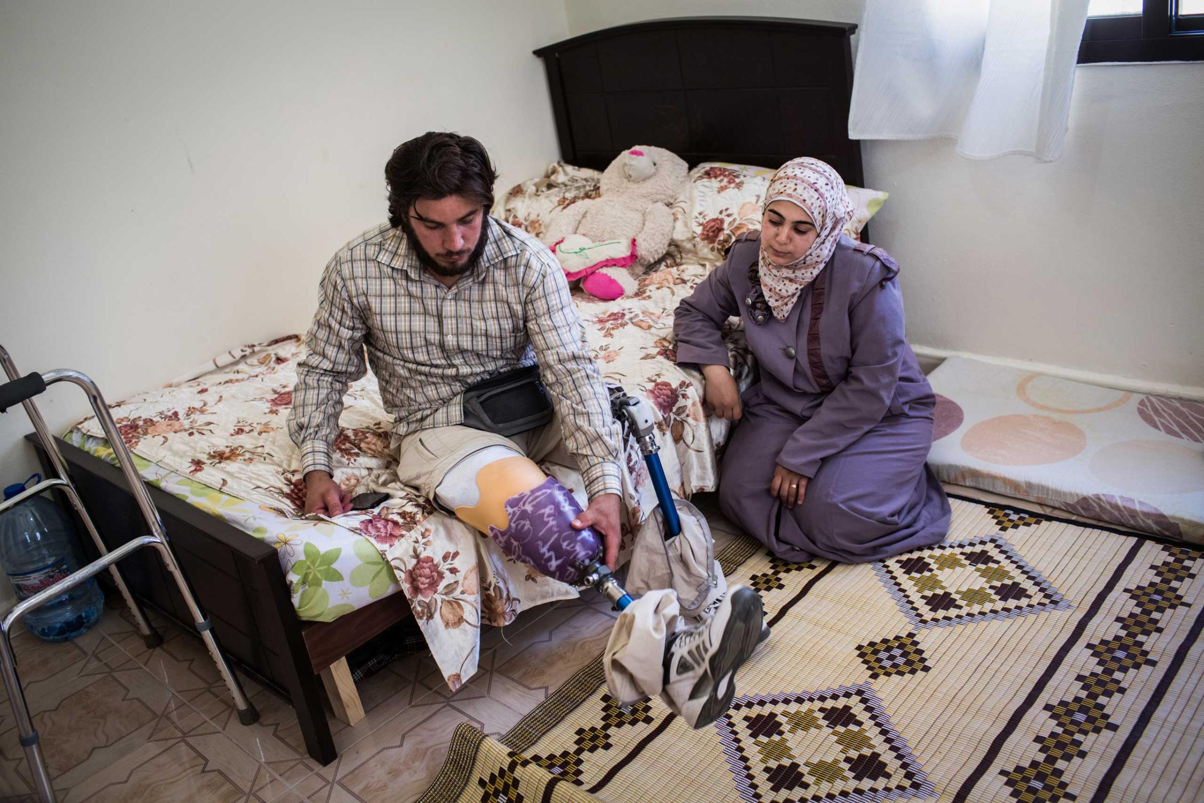 Ahmad, 29, fits his prosthetic with the help of his wife, Lazmiah, at their home in Tripoli, Lebanon, June 17, 2014. Ahmad lost both legs after a mortar attack near his home in Zabadane, Syria. He and his wife volunteer in the area.