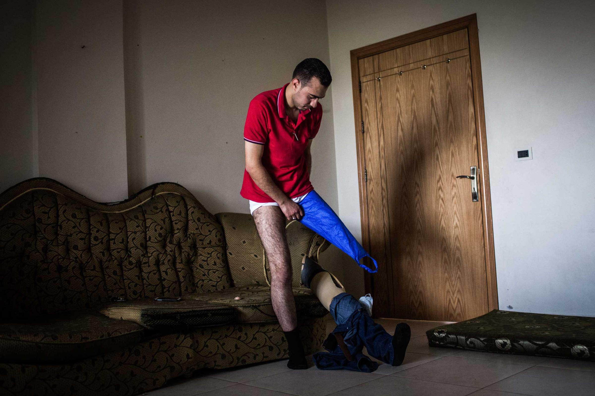 Ihsan fits his prosthetic at home in Qab Elias, Lebanon, June 19, 2014. The dental student, 22, was injured in December 2012 when a bomb fell nearby, leading to two surgeries and the loss of a leg. He continued to volunteer.