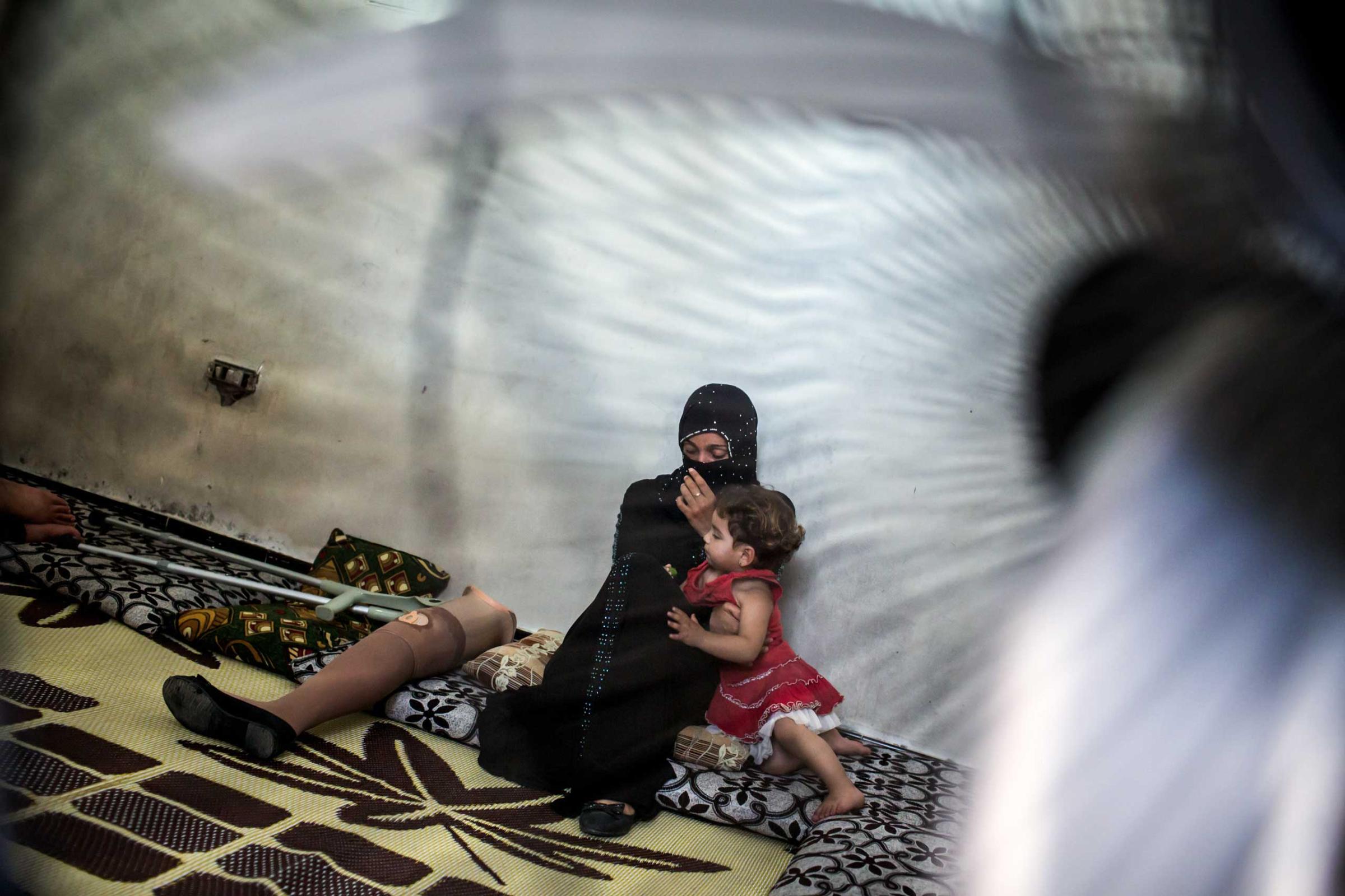Awatef, 25, with her daughter, Sabah, 2, at home in Tripoli, Lebanon, June 24, 2014. She lost her leg in shelling near her home in Homs earlier this year. She walked for the first time in six months: “I keep practicing so it is getting easier.”
