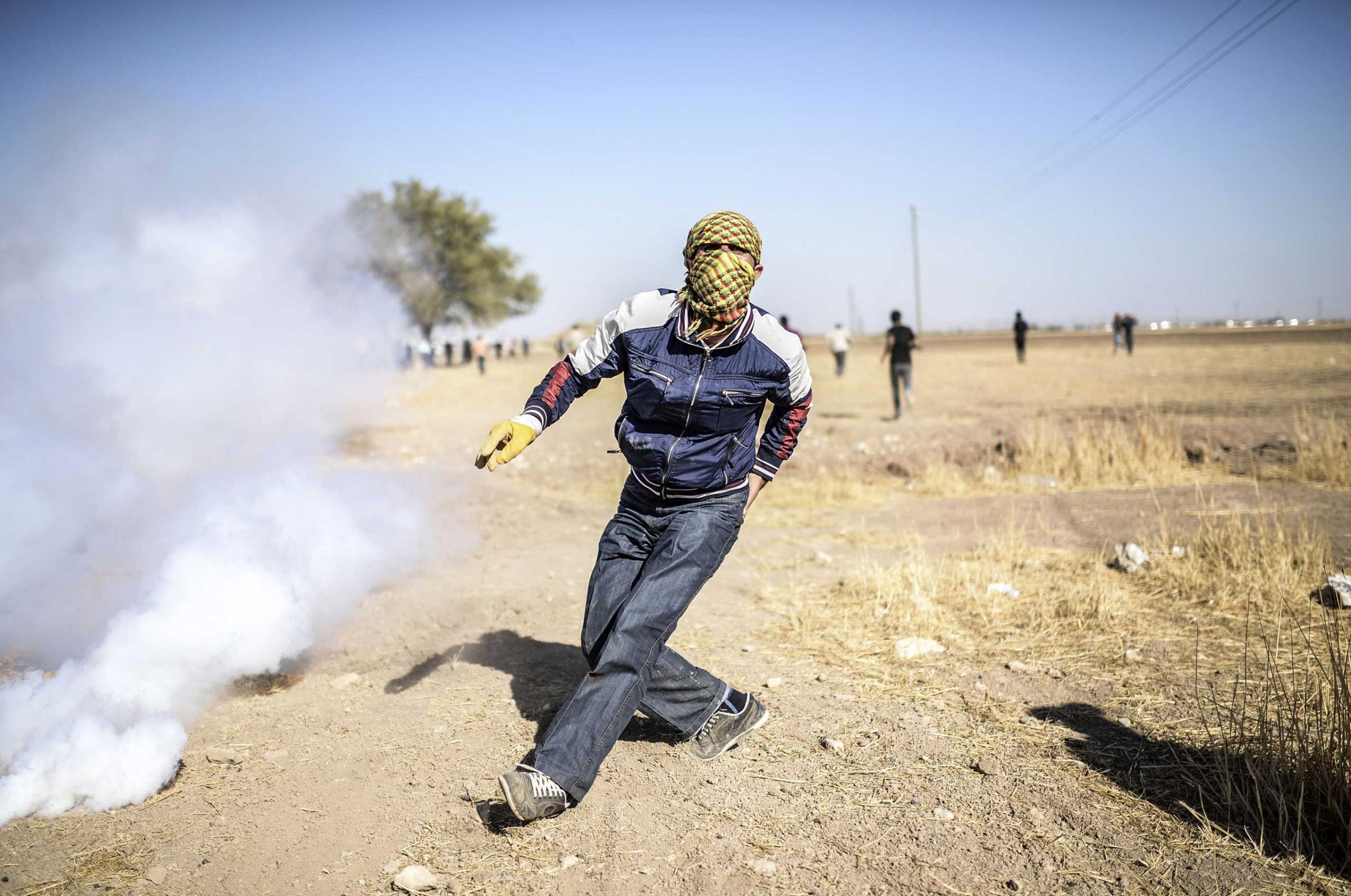 A Kurdish protestors clashes with Turkish soldiers (unseen) near the Syrian border after Turkish authorities temporarily closed the border near the southeastern town of Suruc in Sanliurfa province, on Sept. 22, 2014.