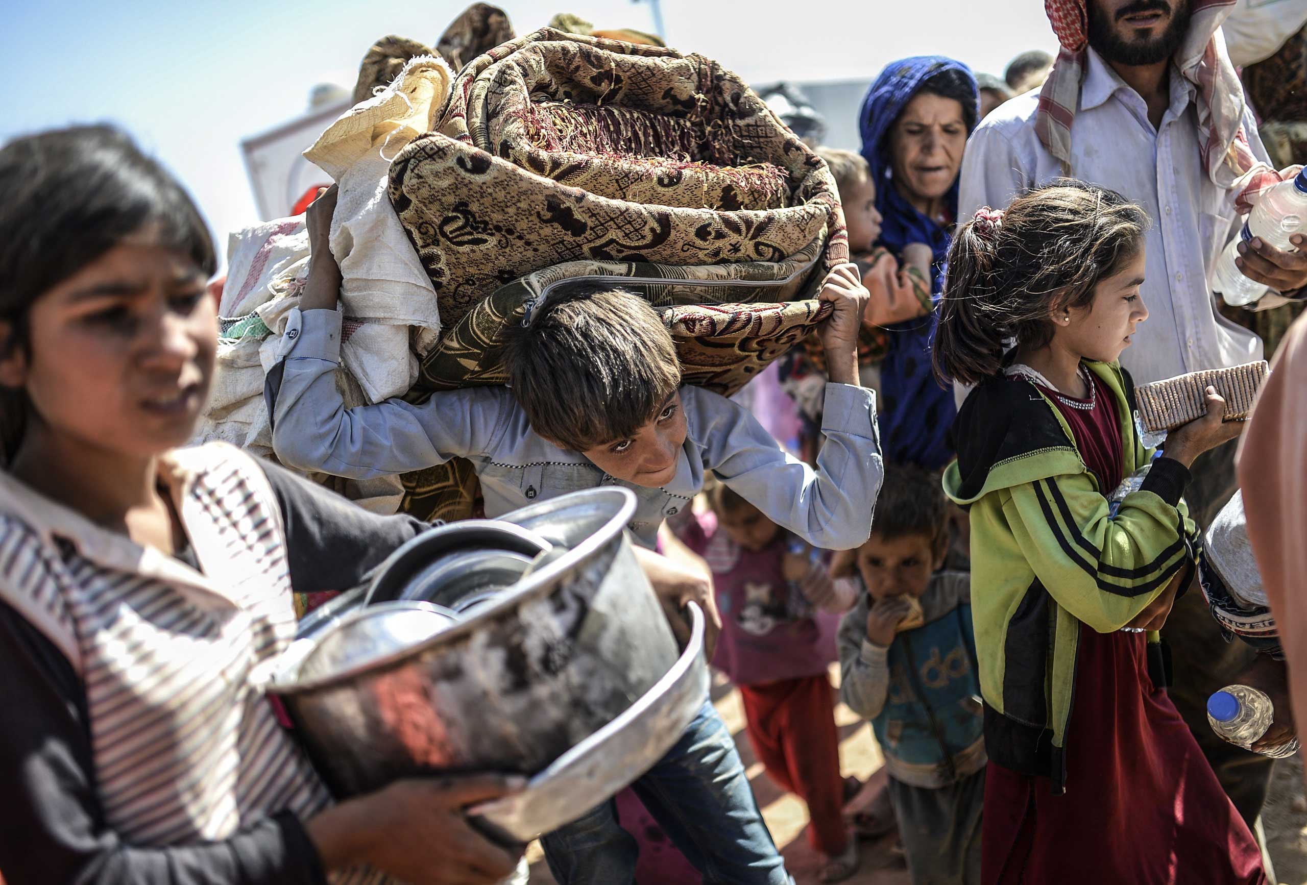 Syrian Kurds carry their belongings as they cross the border between Syria and Turkey at the southeastern town of Suruc in Sanliurfa province on Sept. 23, 2014.