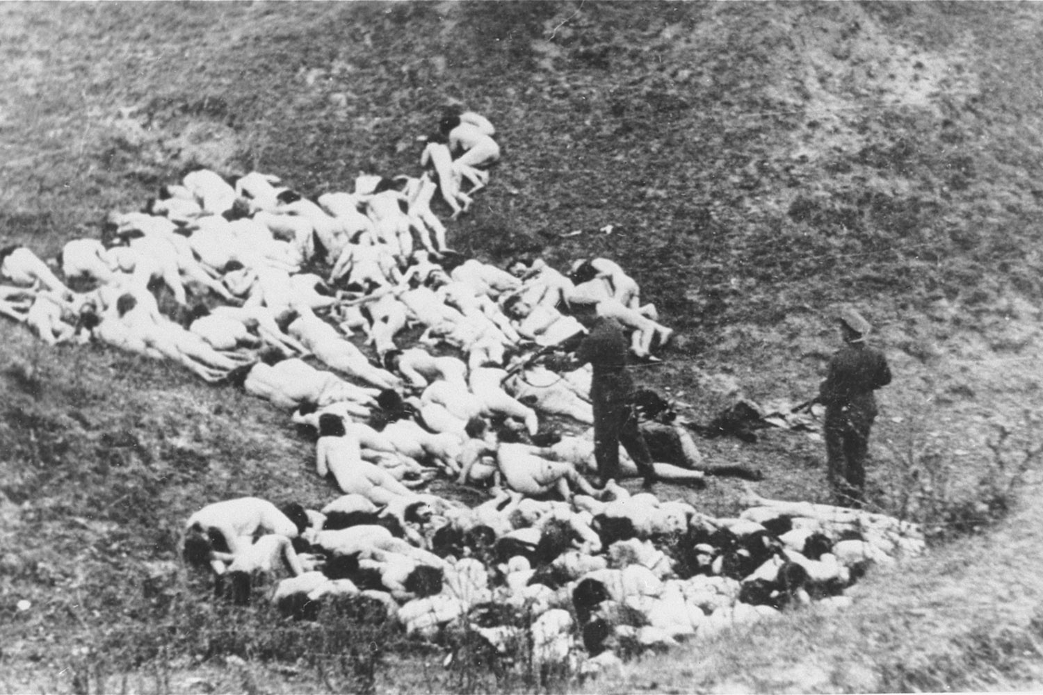 A German police officer shoots Jewish women still alive after a mass execution of Jews from the Mizocz ghetto, former Poland, 1942.