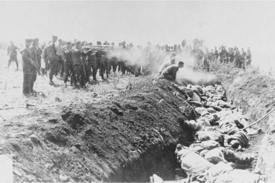 Men with an unidentified unit execute a group of Soviet civilians kneeling by the side of a mass grave, USSR, 1941.