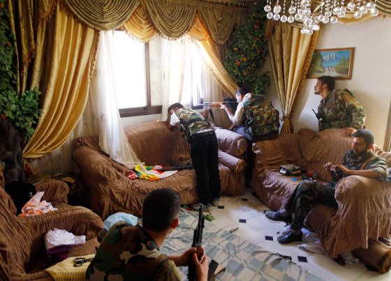 A Free Syrian Army fighter fires his sniper rifle from a house in Aleppo