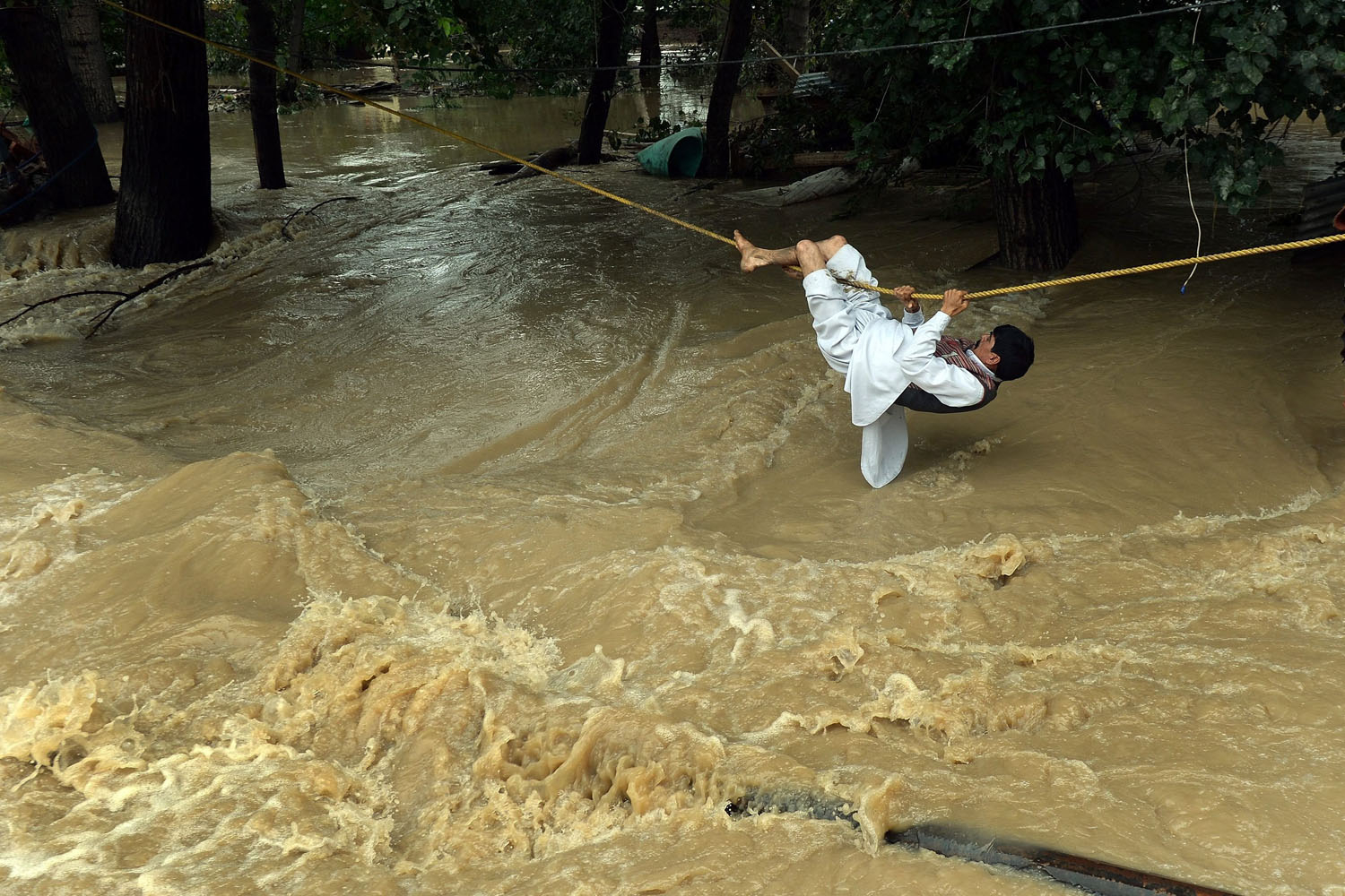 Sept. 9, 2014. An Indian Kashmiri man crosses over flood waters with the use of a rope in Srinagar. Bewildered families, nursing children and clutching meagre belongings, packed into makeshift relief centres after fleeing floods in India and Pakistan that have now claimed more than 400 lives.