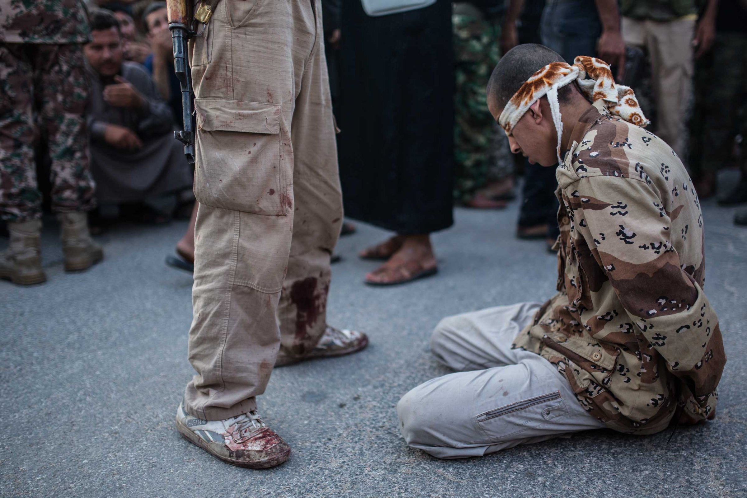 A young Syrian man kneels blindfolded before anti-regime rebels publicly executed him in the town of Keferghan, near Aleppo, on August 31, 2013.