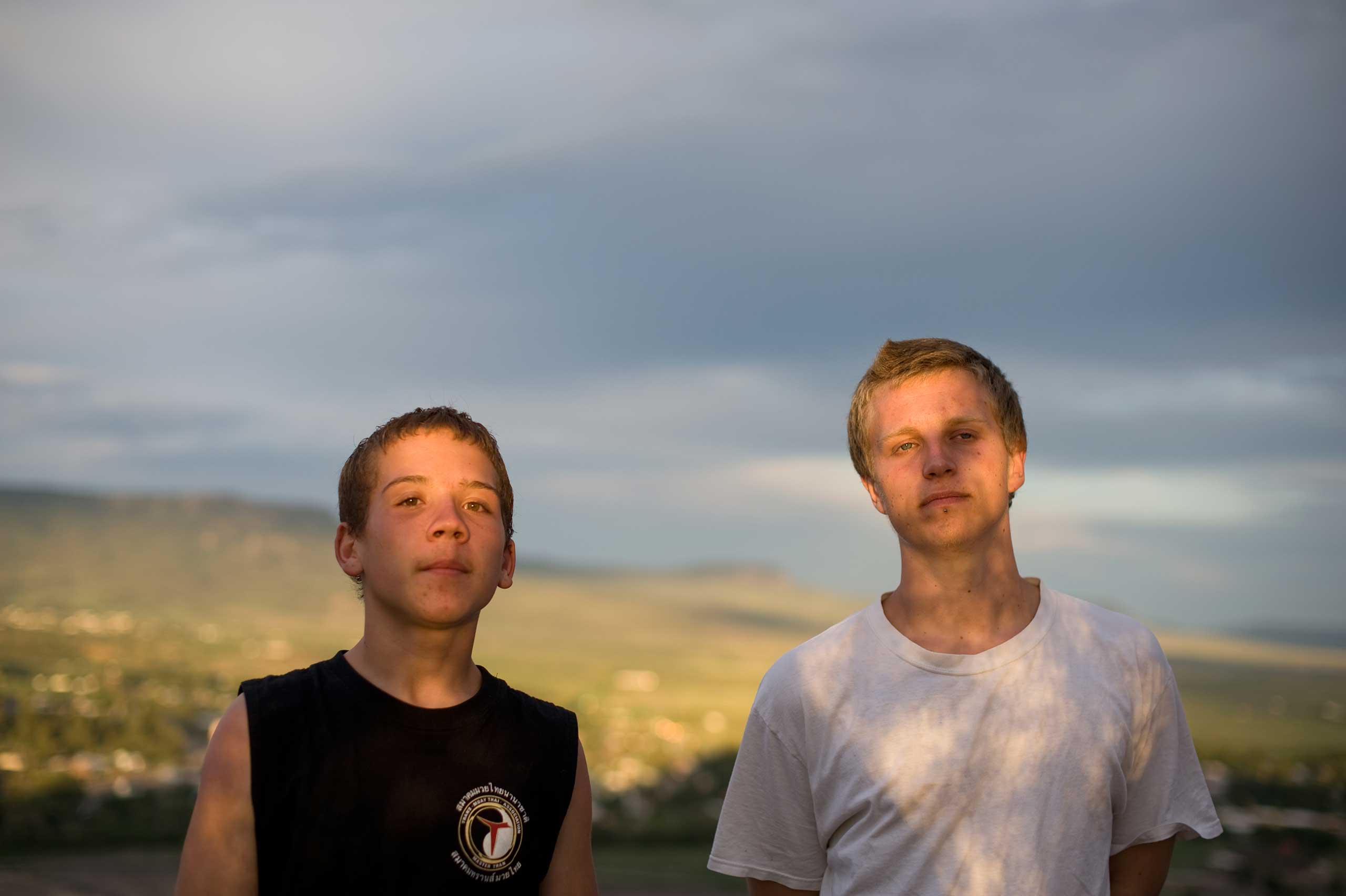 Brothers Vinny and David stand together as the sky darkens before a summer storm.