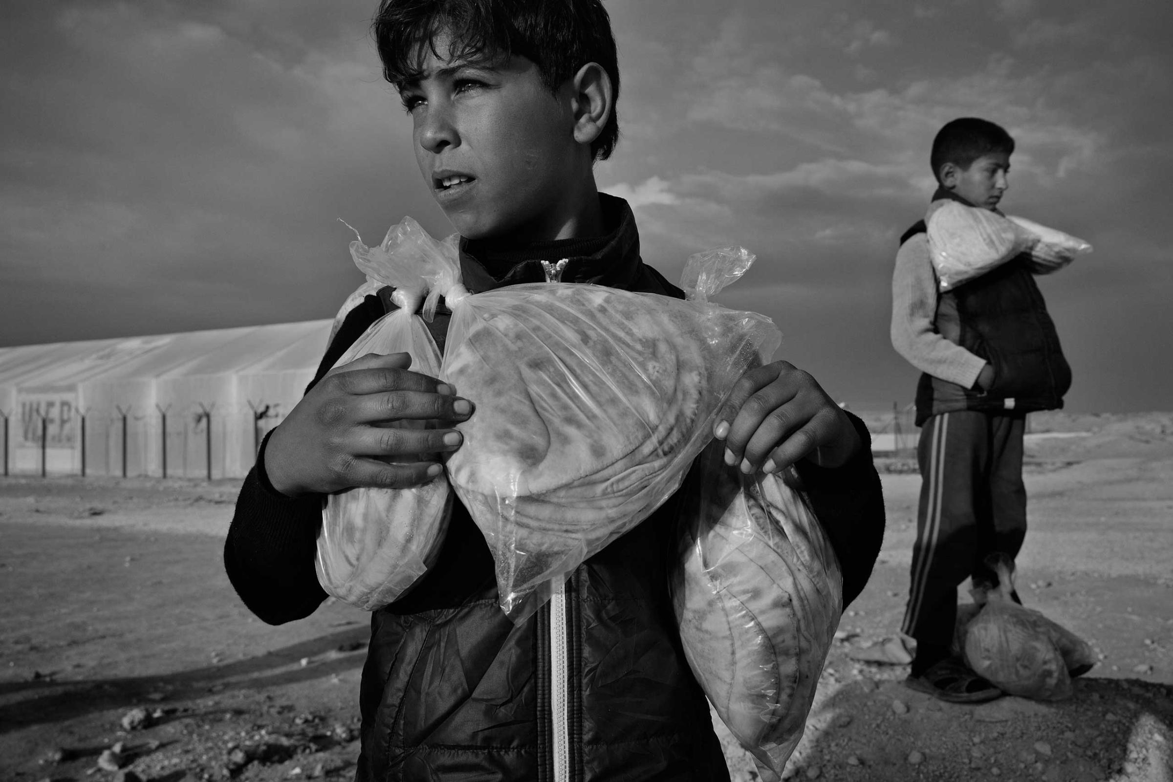 December 2013. Za'atari refugee camp, Jordan. Syrian boys carry their daily bread ration supplied by the World Food Programme.