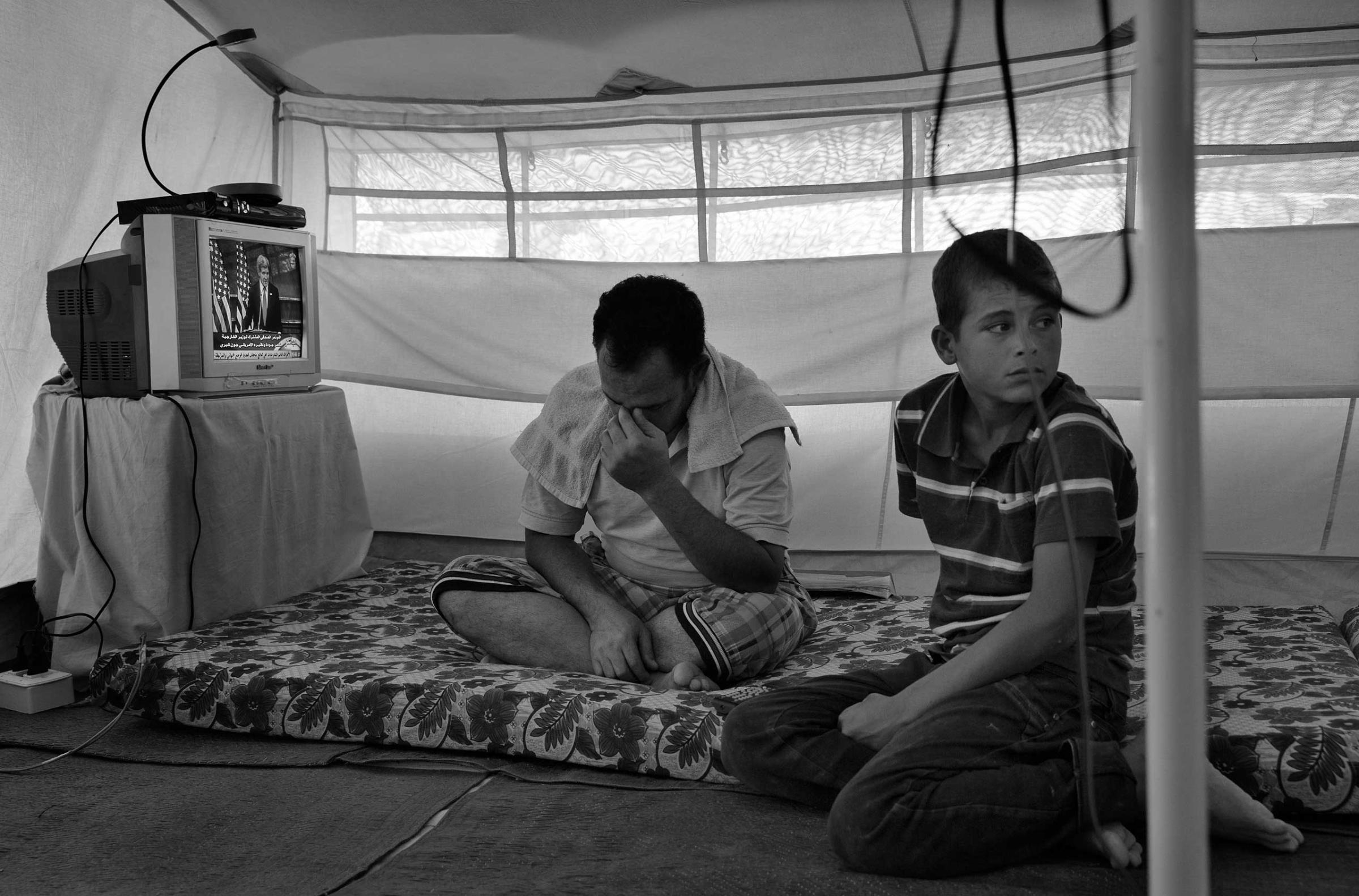 December 2013. Za'atari refugee camp, Jordan. A father and son in a camp tent.