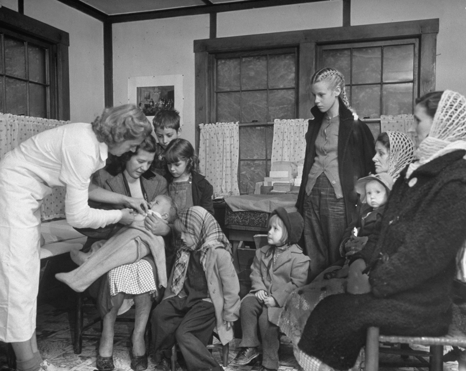 At Possum Bend Nursing Center a young patient gets whooping cough and diphtheria shots from nurse Lydia Thompson while other children and their mothers wait.