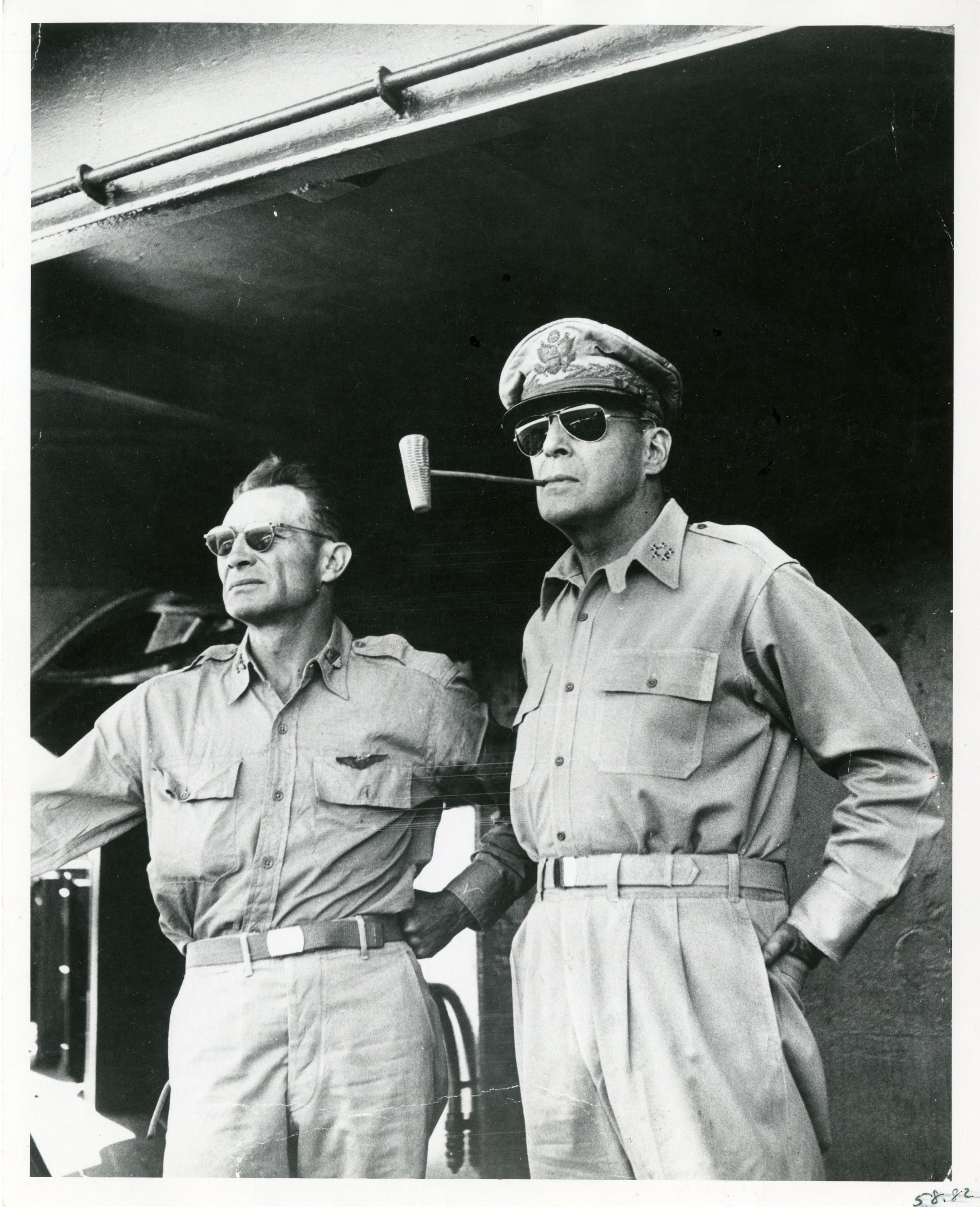 Text from the back of the print in LIFE's archives: "Gen. Douglas MacArthur smoking corn cob pipe on deck of ship w. aide Col. Lloyd Lehrbas, en route to USAF landing site at Lingayen Gulf in victorious ('I Shall Return') WWII return to Philippine Island site of earlier defeat."