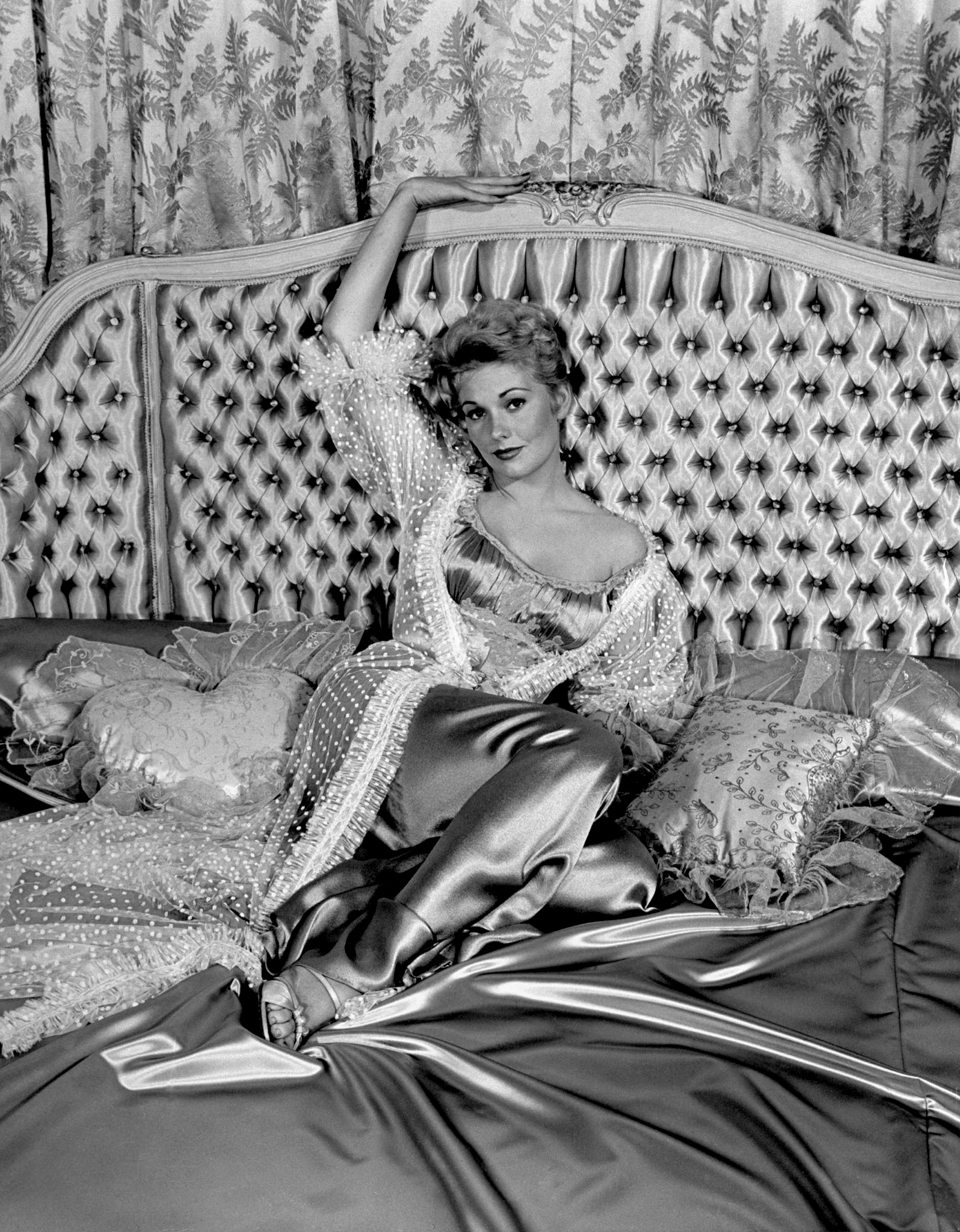 Kim Novak, 21, lounging on satin bed, 1954.