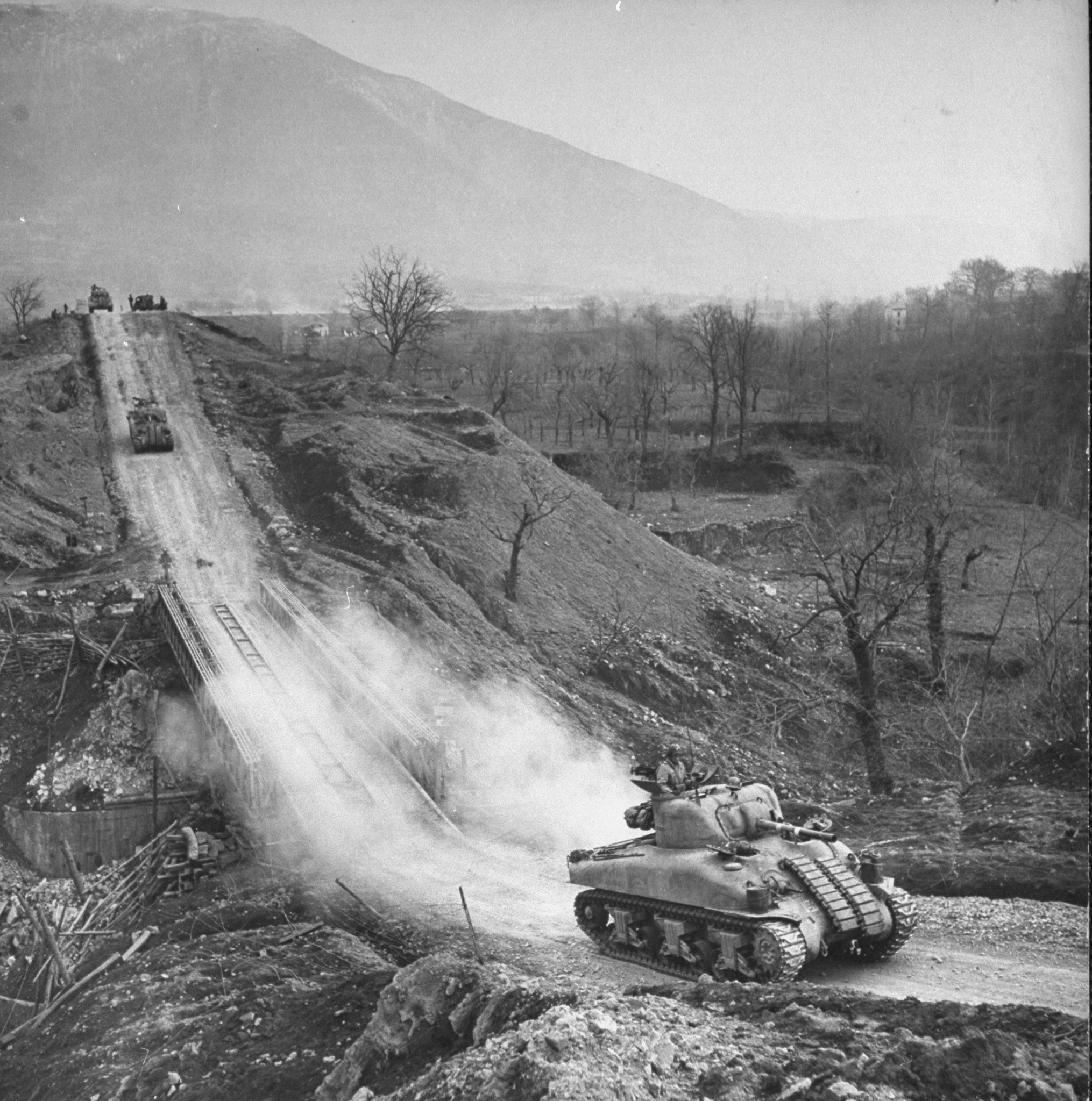 American M4 Sherman tanks rumble across an Allied-built bridge during the push to take the town of Cassino, Italy, 1944.