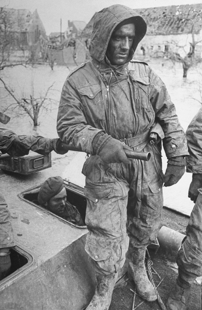 A weary Canadian soldier stands atop a stalled tank amid flooding in the Netherlands, 1945.