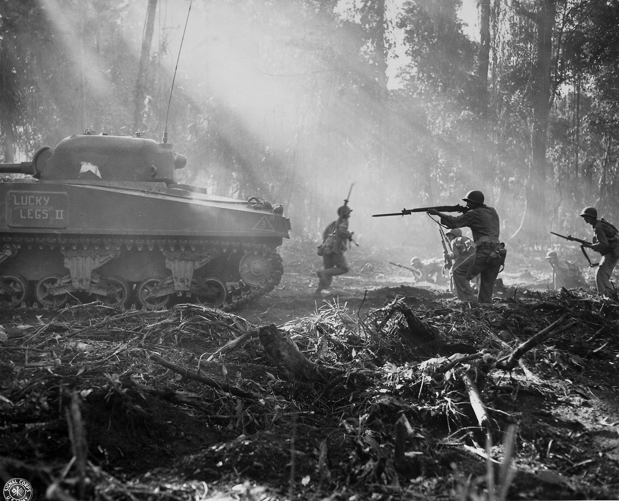 American soldiers use a Sherman tank for cover as it and they advance on Japanese positions during the fight to take Bougainville, Solomon Islands, 1944.