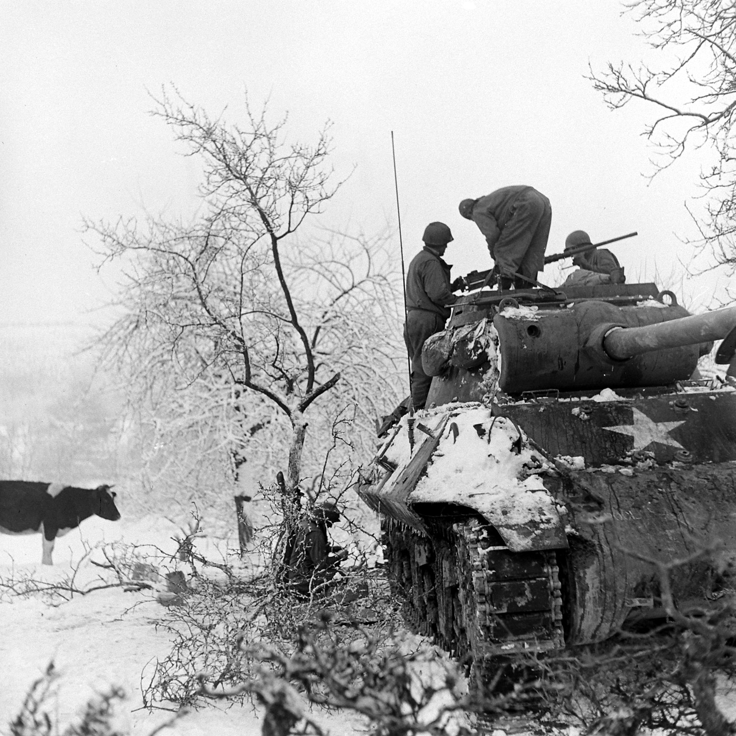 American soldiers aboard a tank in a snow-covered Ardennes field, Battle of the Bulge, December 1944.