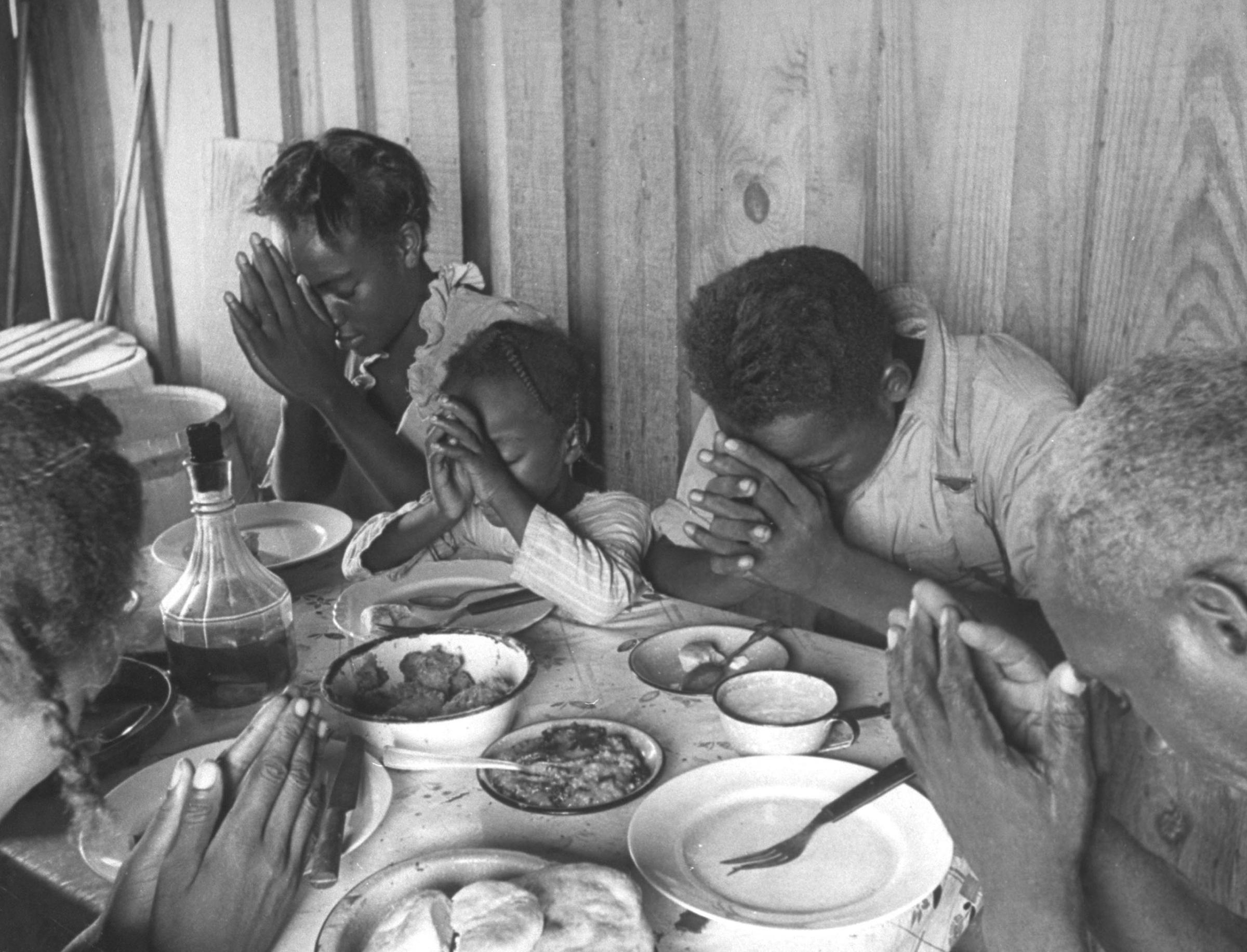 Sharecropper Lonnie Fair and his family praying before a meal, Mississippi, 1936.