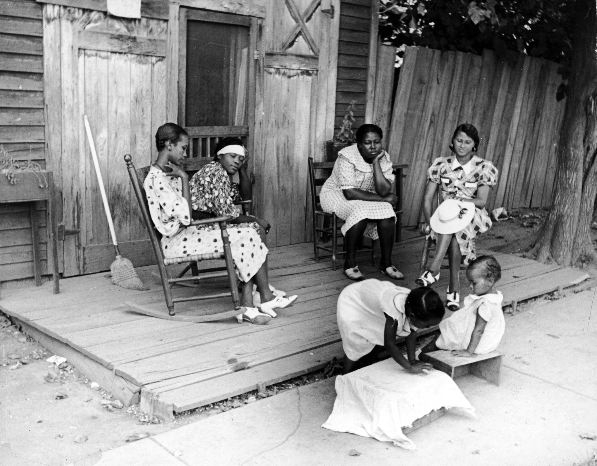 Women on porch, watching children play, Mississippi, 1936.