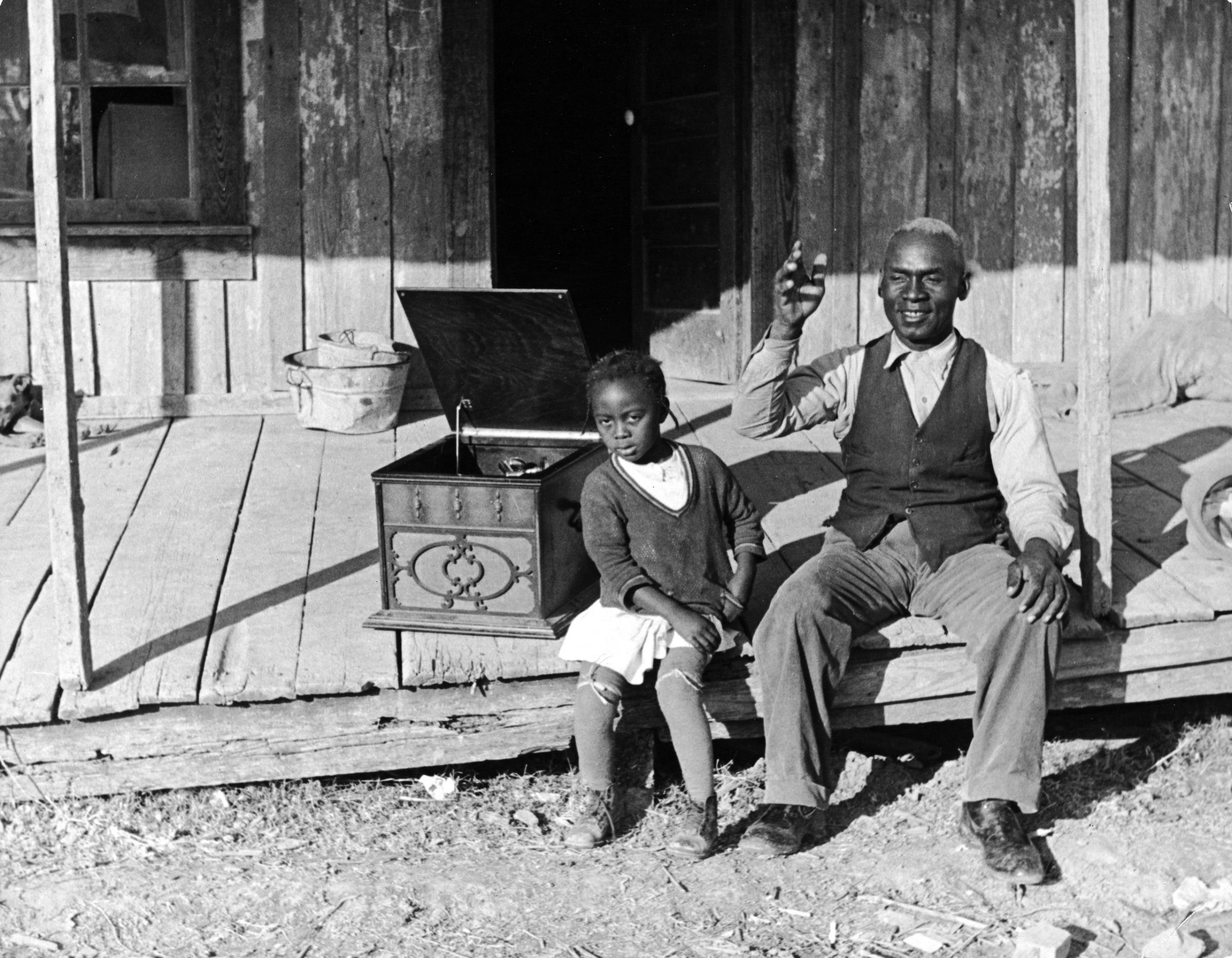 Lonnie Fair and his daughter listen to a Victrola on their sharecropping farm in Mississippi, 1936.