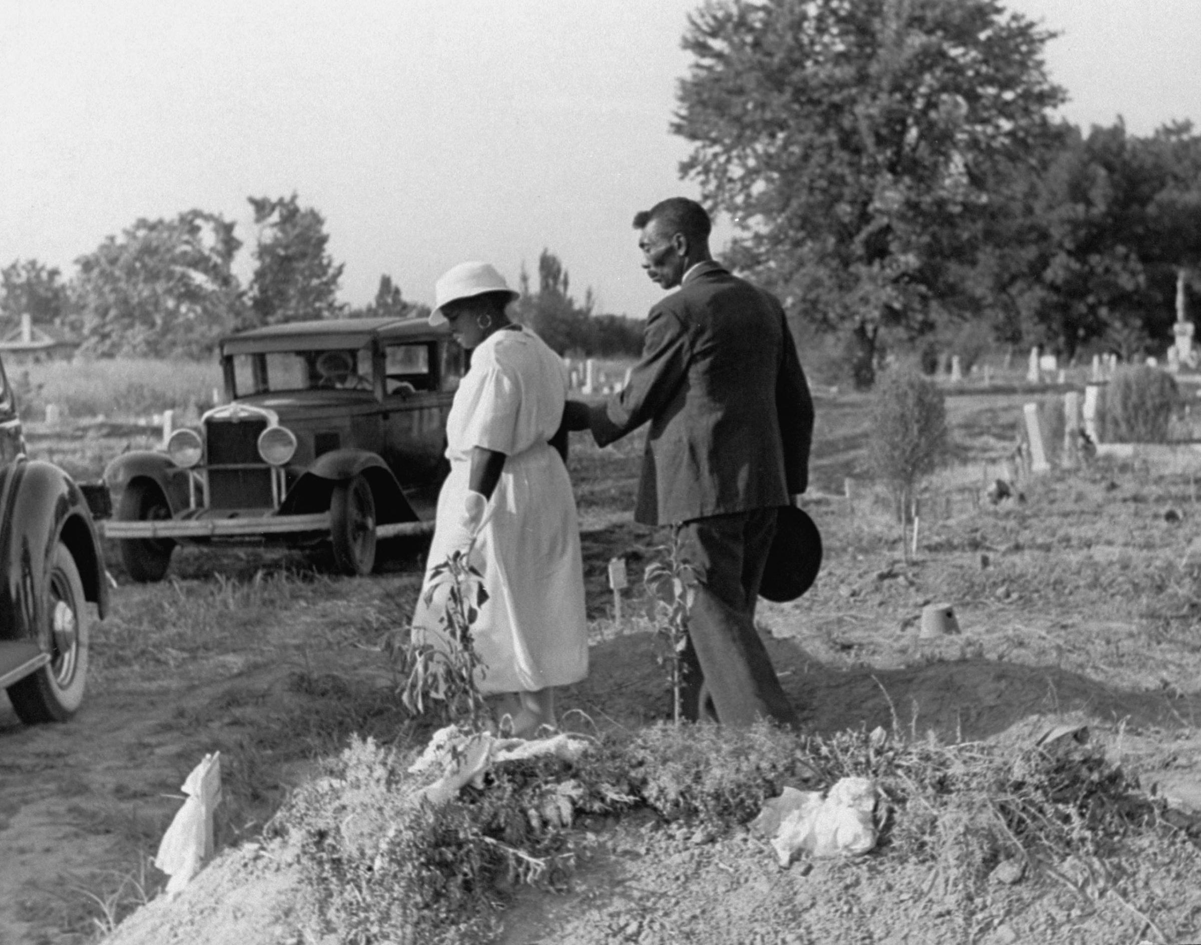 Grieving widow being escorted from the gravesite of her late husband after his burial service, Mississippi, 1936.