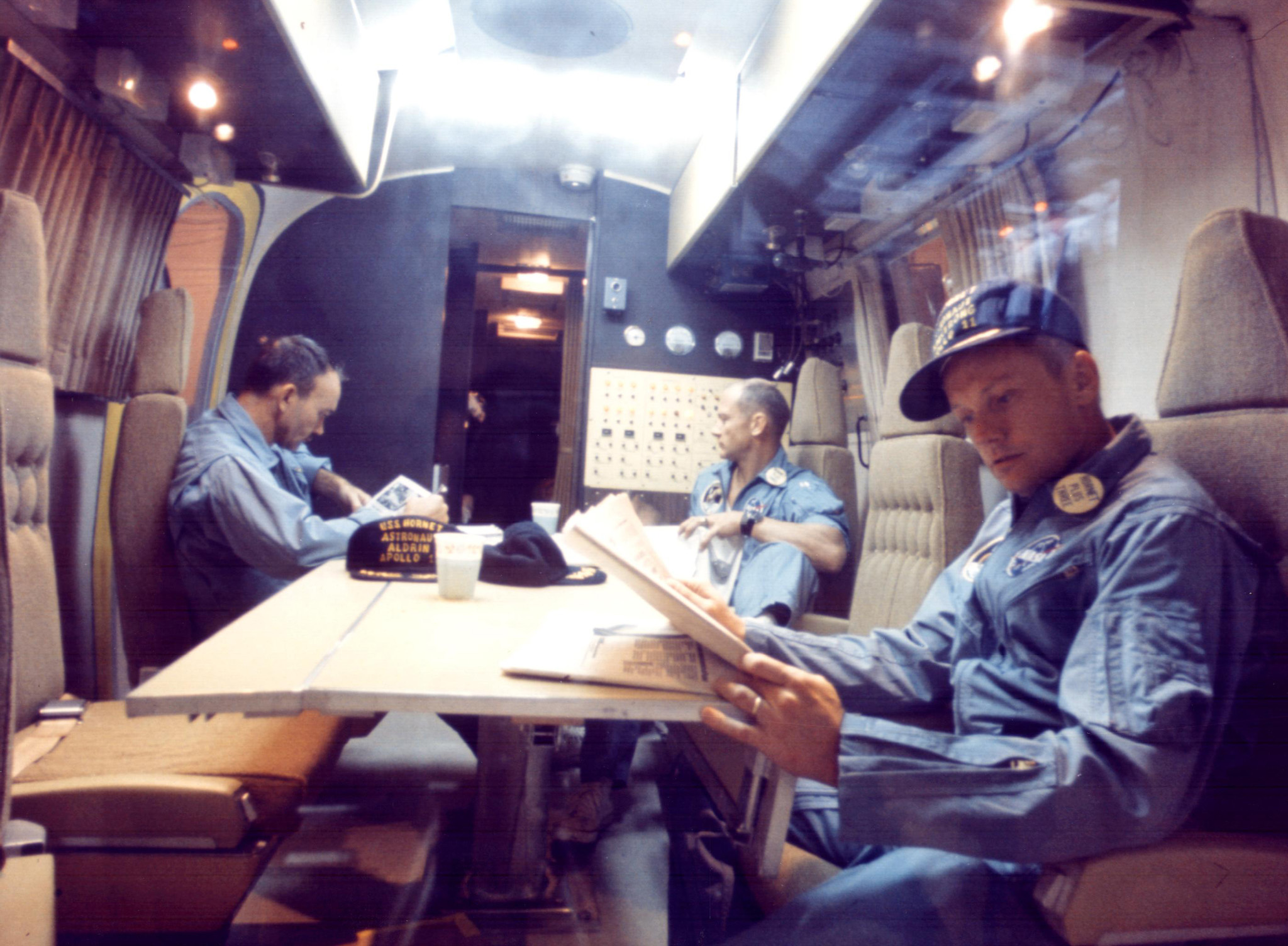 Within the Mobile Quarantine Facility, Apollo 11 astronauts (left to right) Michael Collins, Buzz Aldrin and Neil Armstrong relax following their successful lunar landing mission. They spent two-and-a-half-days in the quarantine trailer en route from the USS Hornet to the Lunar Receiving Laboratory at the Manned Spacecraft Center in Houston. The Hornet docked at Pearl Harbor where the trailer was transferred to a jet aircraft for the flight to Houston.