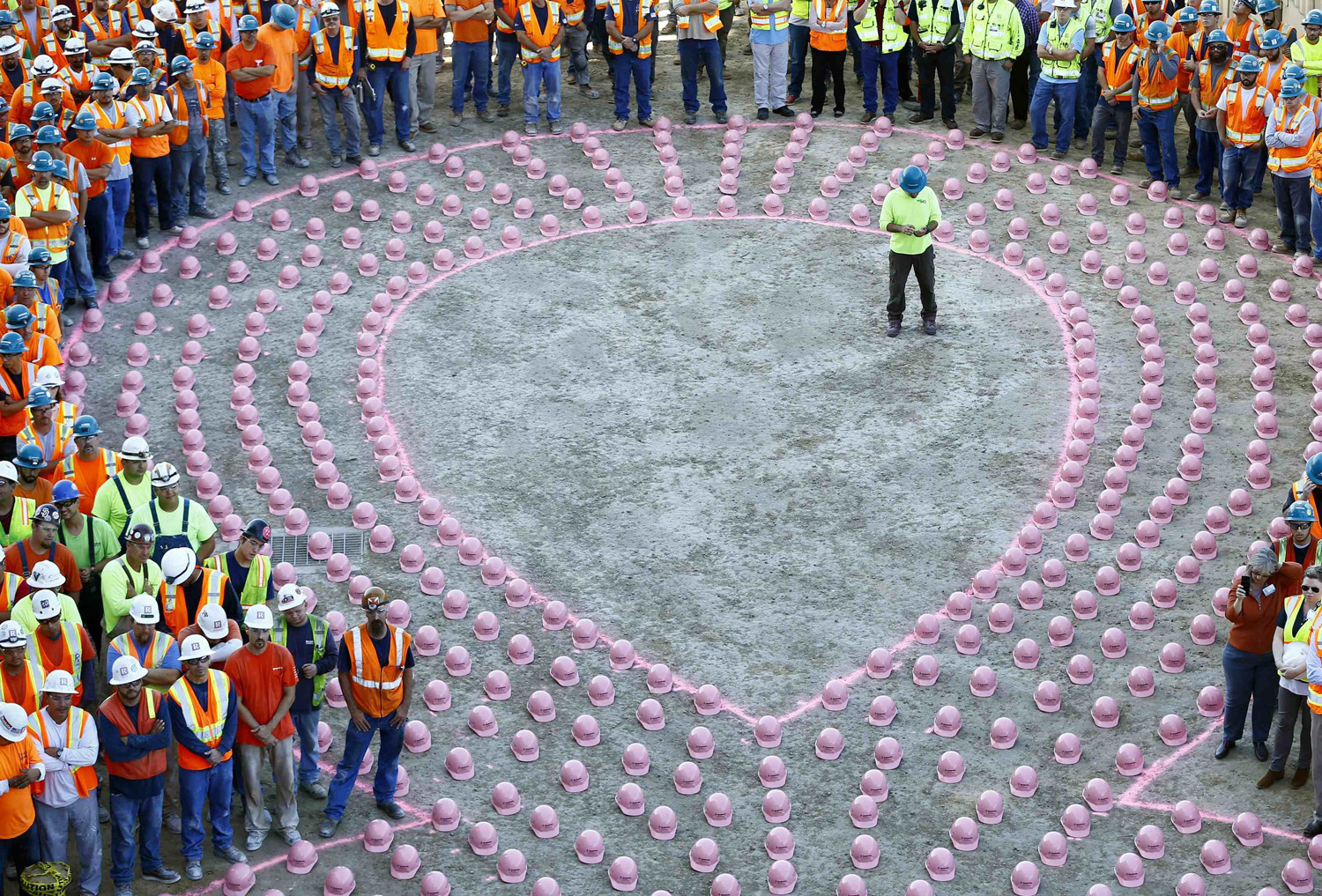 Construction workers from EMCOR Dynalectric wait to put on pink hard hats and be part of a giant pink ribbon formation to promote the start of Breast Cancer Awareness Month, at the UC San Diego Jacobs Medical Center construction site in La Jolla, Calif. on Sept. 30, 2014.