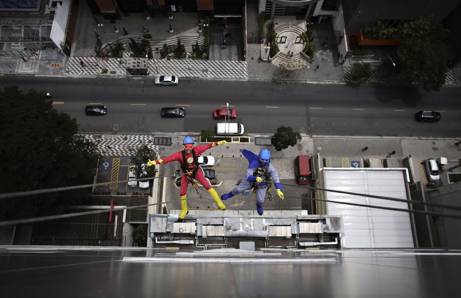 Men dressed as Batman and Flash prepare to clean the glass facade of Hospital Infantil Sabara before meeting with patients of the children's hospital in Sao Paulo
