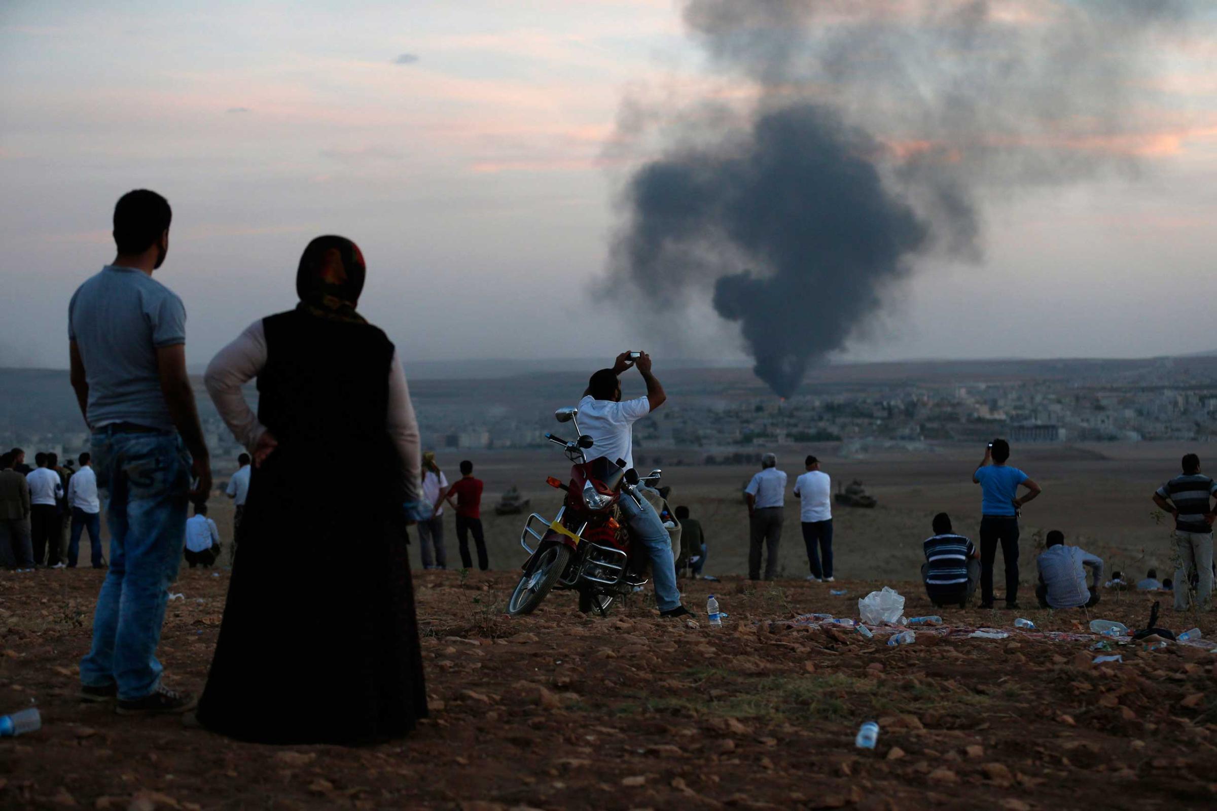 Smoke rises in the Syrian town of Kobani as Turkish Kurds watch near the Mursitpinar border crossing on the Turkish-Syrian border in the southeastern town of Suruc