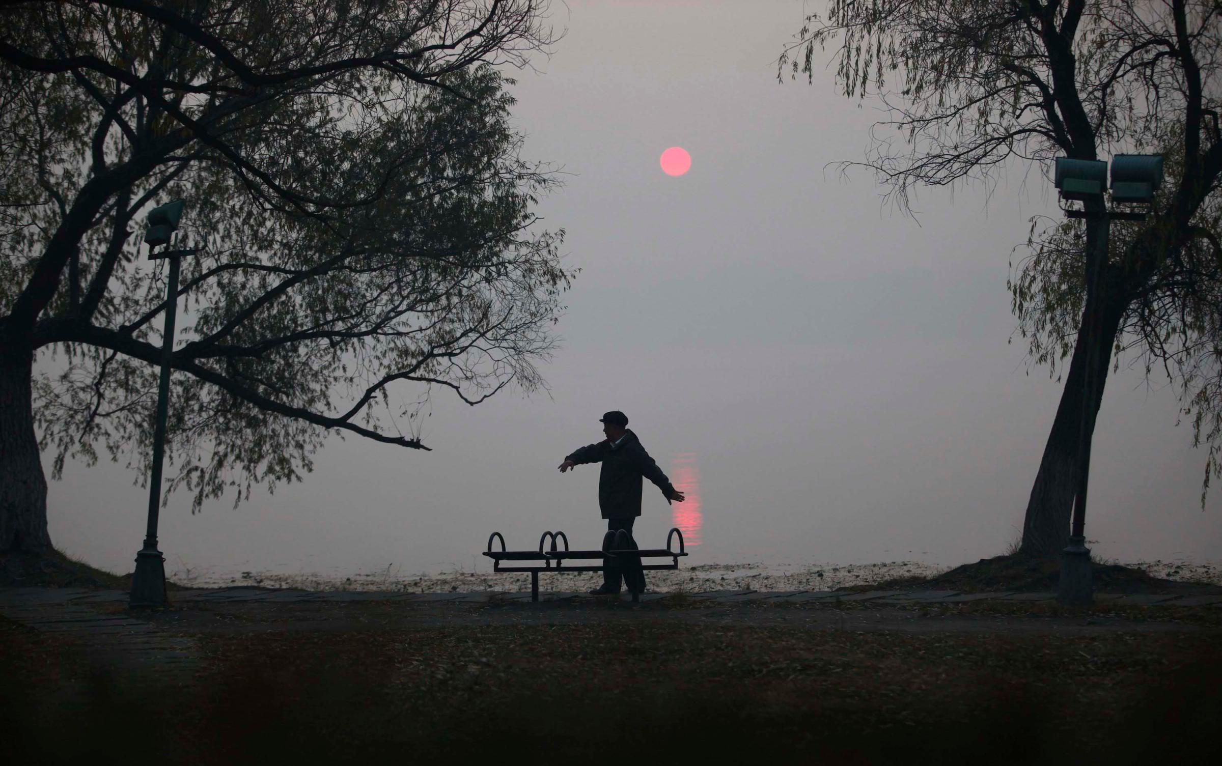 A man does his morning exercise on a polluted day by the side of a lake at Nanhu Park in Changchun, Jilin province, China on Oct. 22, 2014.