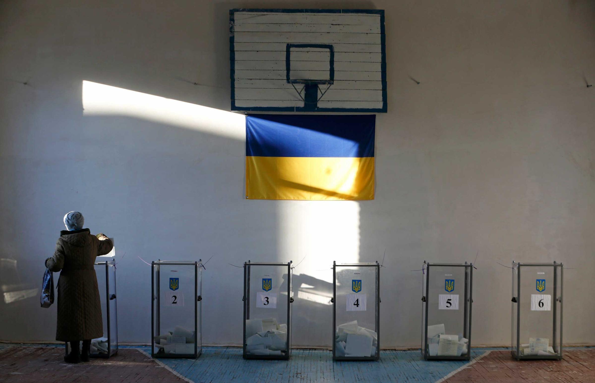 A woman casts a ballot during a parliamentary election at a school gym in the village of Semyonovka near Slaviansk