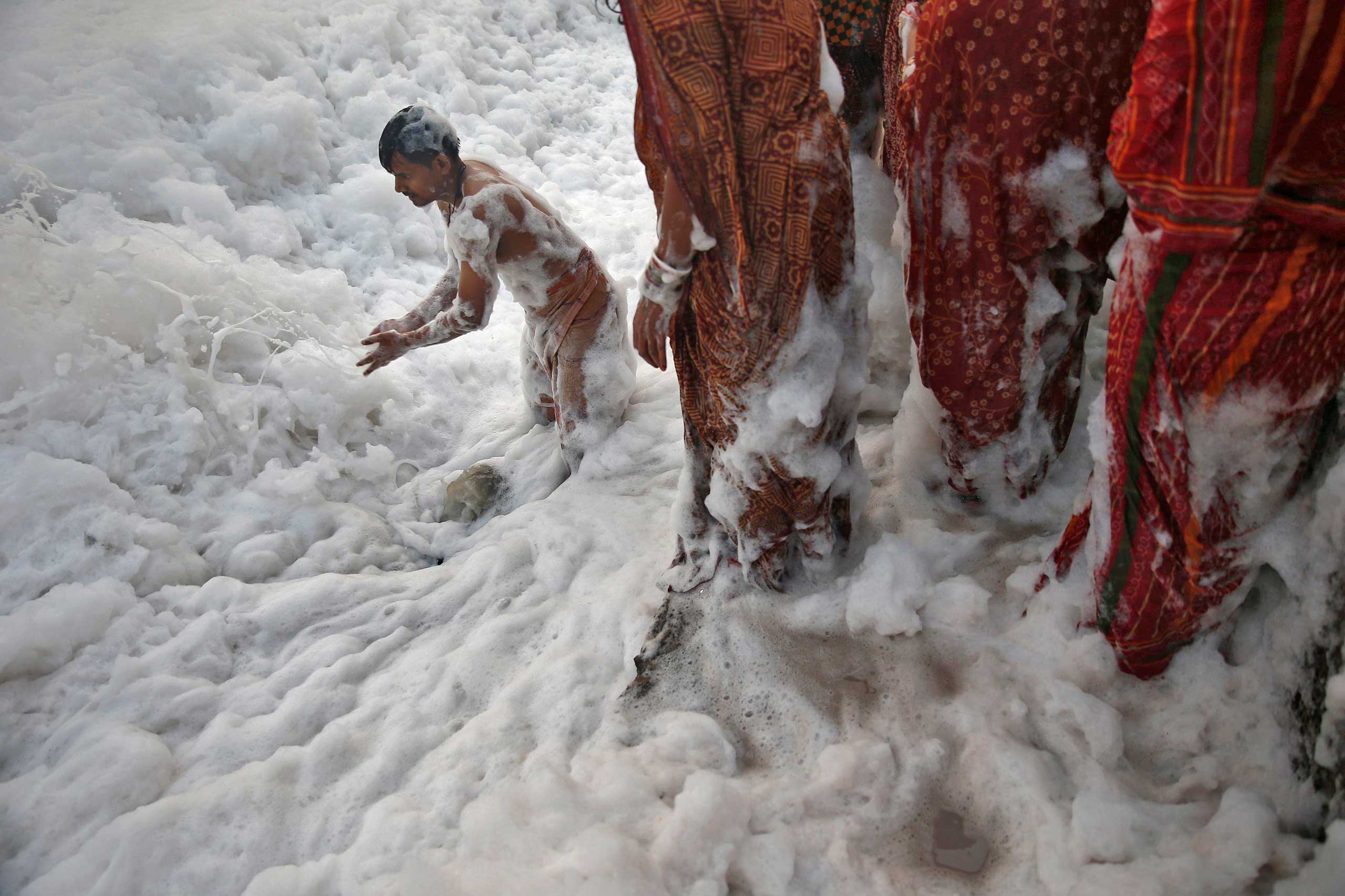 Oct. 30, 2014. A Hindu devotee pushes the foam away to make space for other devotees to worship the Sun god Surya in the polluted waters of the river Yamuna during the Hindu religious festival of Chatt Puja in New Delhi. Hindu women fast for the whole day for the betterment of their family and the society during the festival.