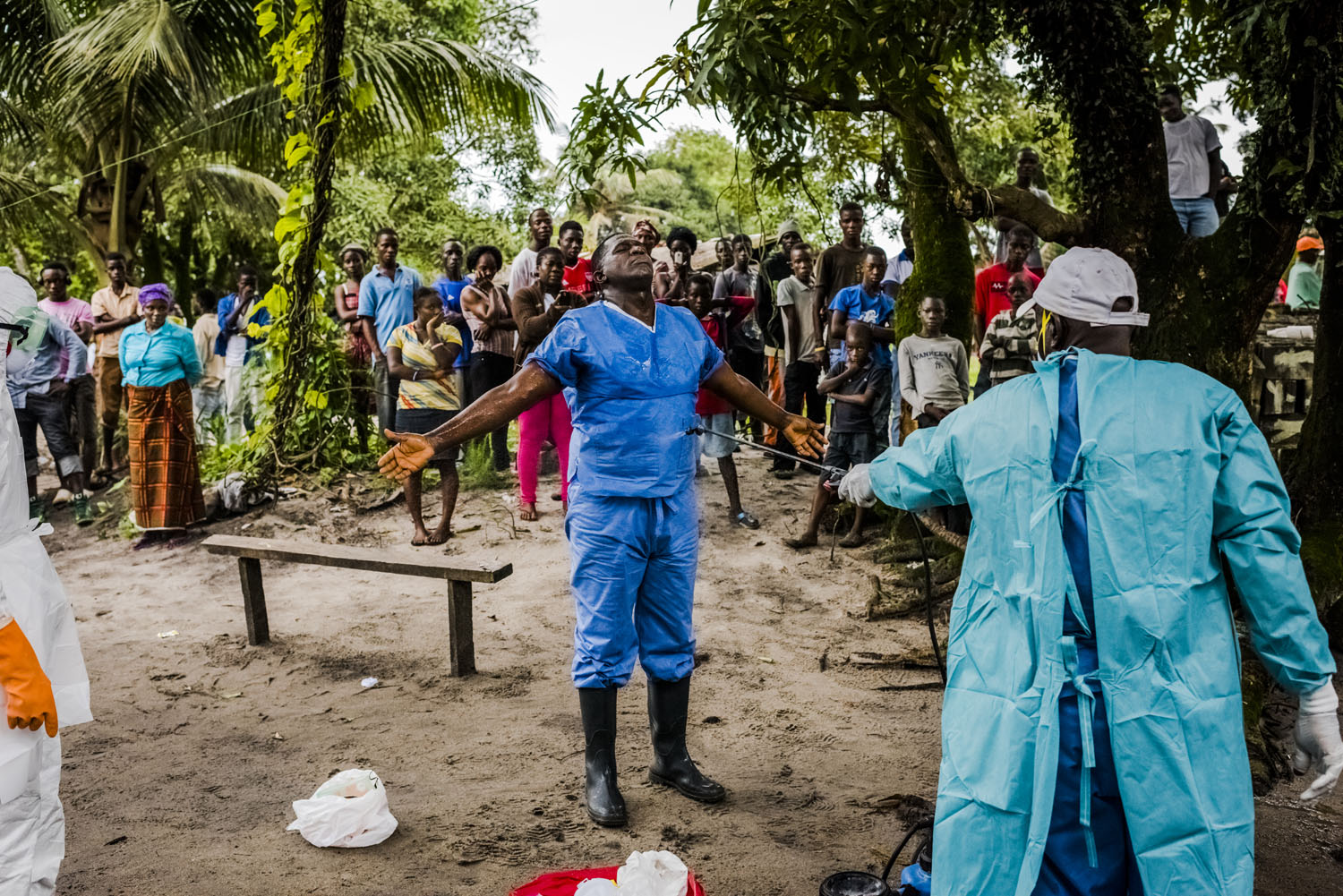 A member of a Liberian Red Cross burial team is disinfected, with chlorine sprayed on by a colleague, after having removed the body of a man, a suspected Ebola victim from his home on Sept. 6, 2014 in Monrovia, Liberia.