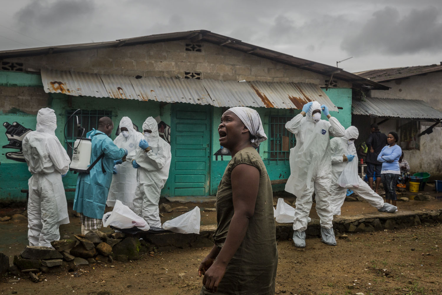 A relative grieves as a Liberian Red Cross burial team, dress themselves in full protective clothing, prior to removing the body of a suspected Ebola victim, Ofori Gweah, 62, on Sept. 18, 2014 in central Monrovia, Liberia.